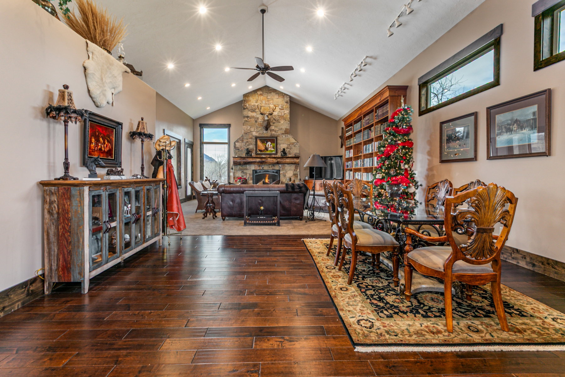 Spacious interior featuring wood-finish flooring, vaulted ceilings with recessed lighting, and a stone fireplace
