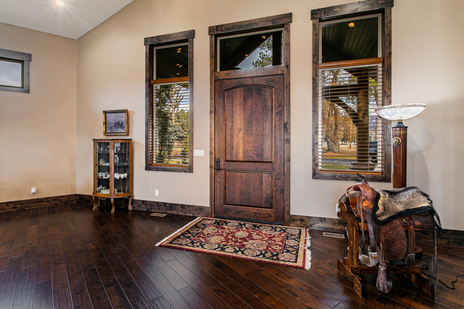 Vaulted ceiling entry featuring dark wood-finish flooring, a solid wood door with side window panels, and rustic wood trim