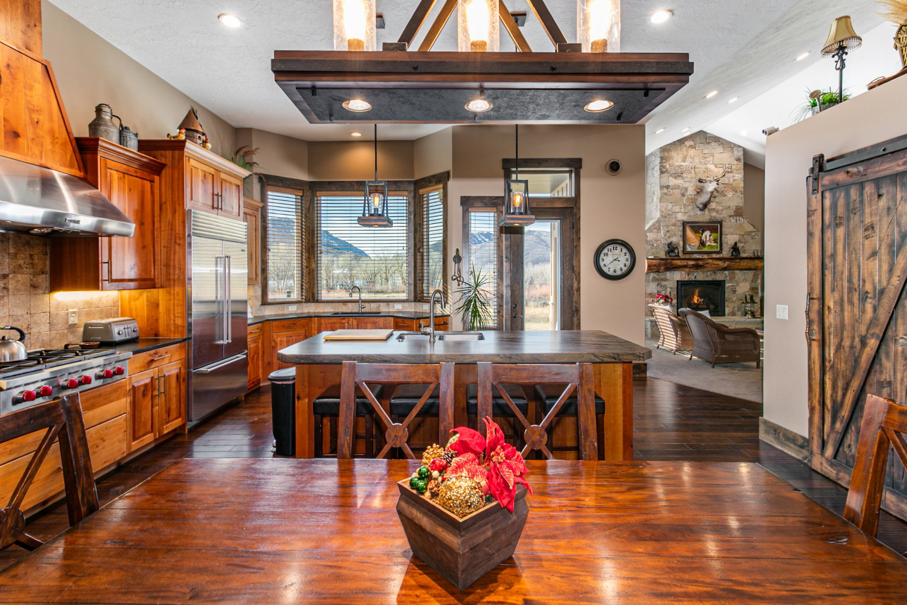 Expansive kitchen featuring wood cabinetry, stainless steel appliances, and a central island with seating