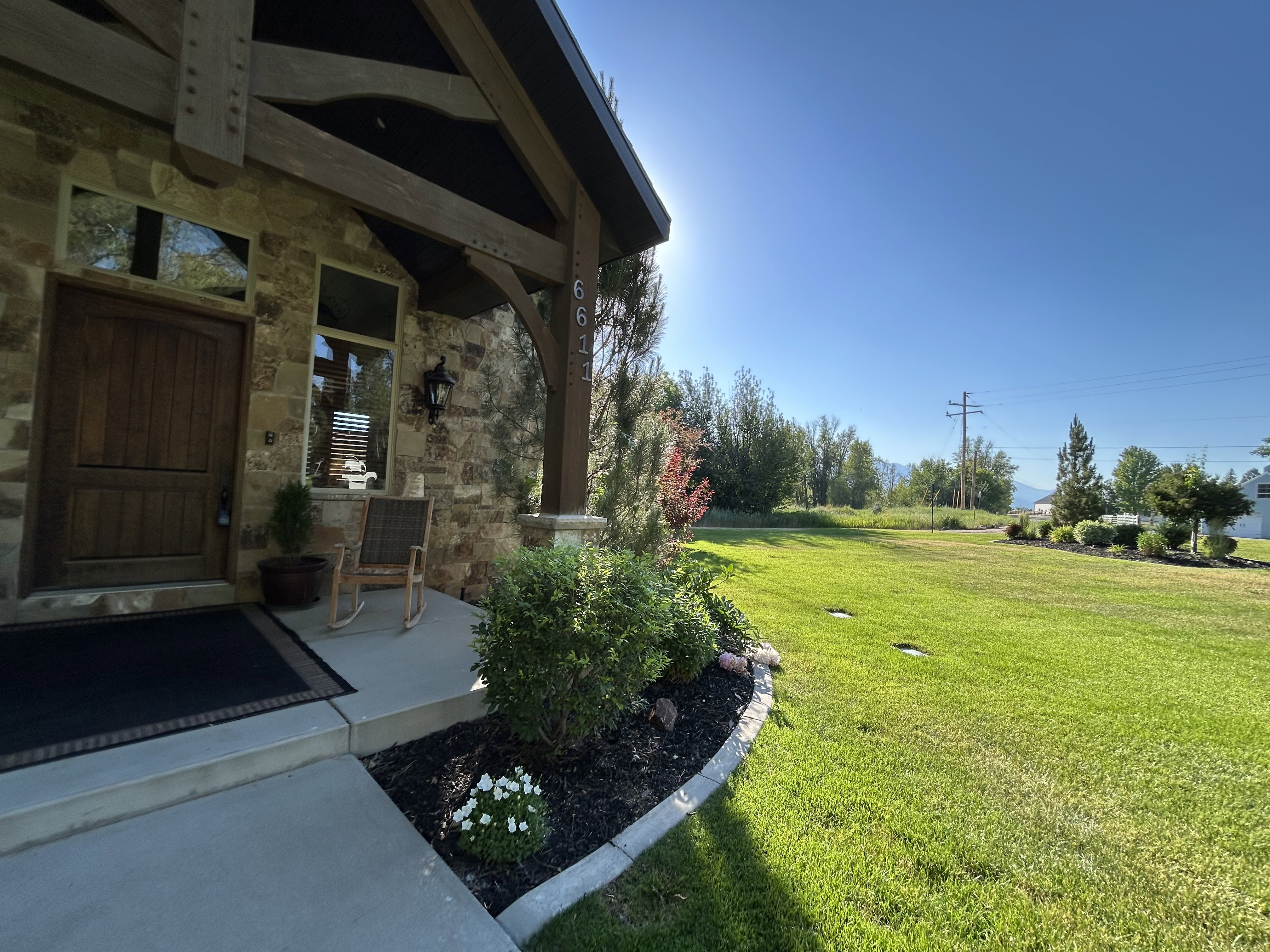 Stone facade home featuring a prominent wood front door with decorative paneling and an overhead transom window