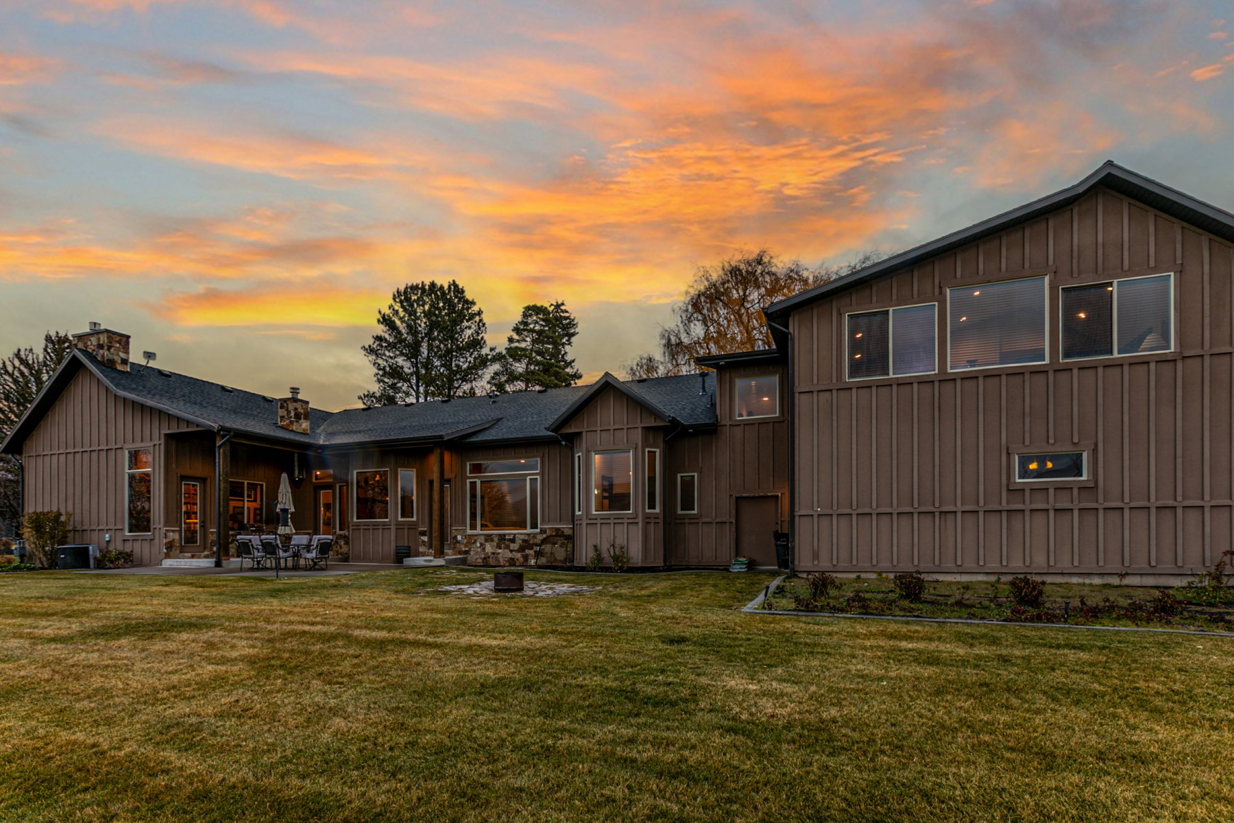 Expansive backyard featuring a manicured lawn, stone accents, and a large patio area