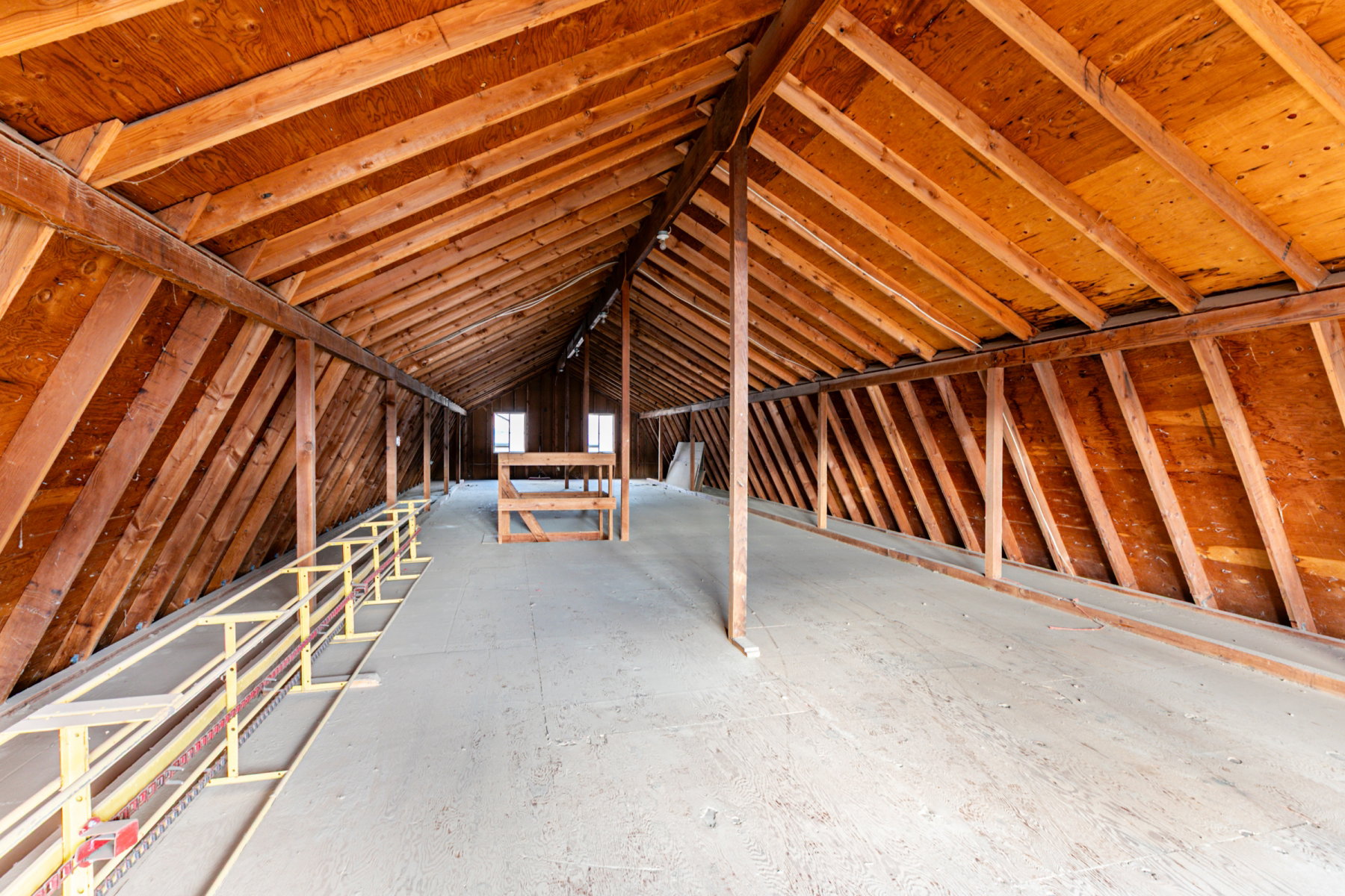 Spacious attic area featuring exposed wood beams and sloped ceilings