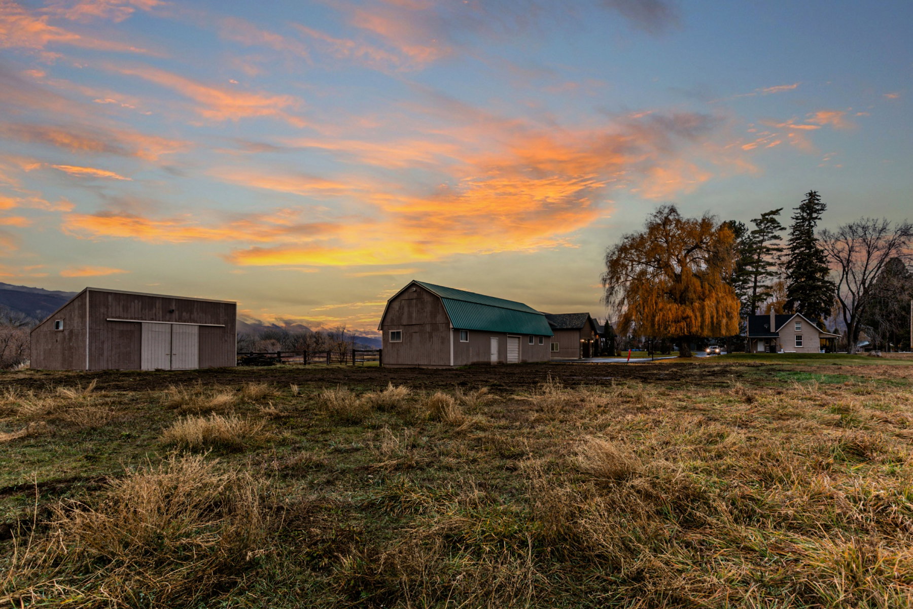 Expansive rural property featuring two outbuildings with metal roofs, a barn-style structure, and a secondary dwelling