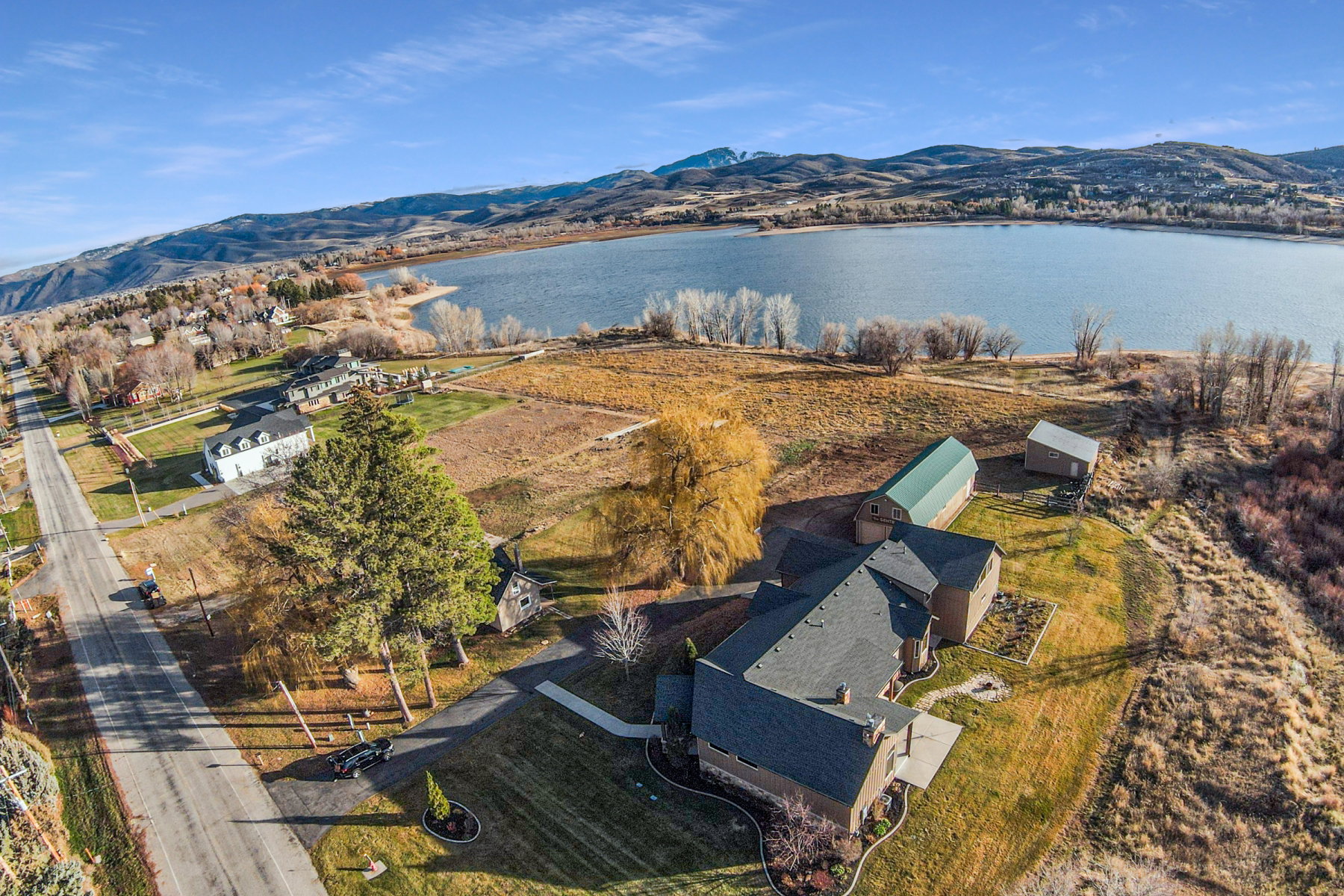 Aerial view highlighting the property's expansive grounds, situated near a substantial body of water with distant mountains