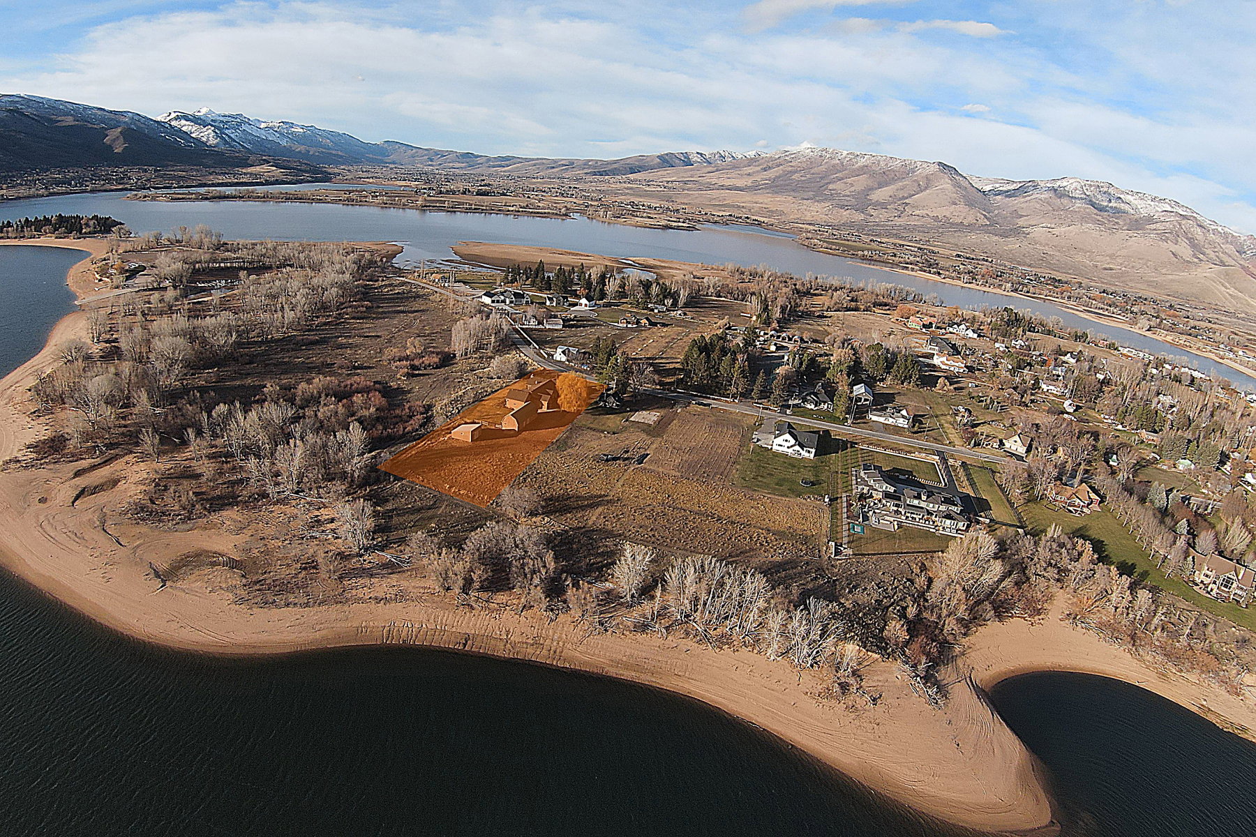 Expansive property featuring a waterfront location, a prominent cleared building site, surrounding natural landscapes, and distant mountains