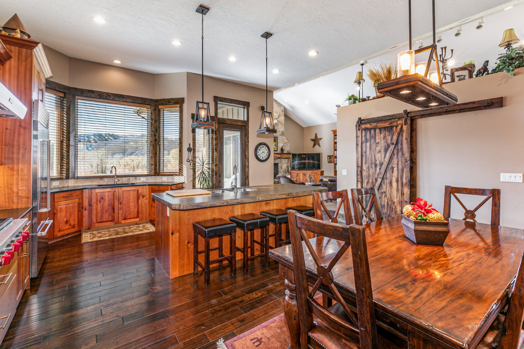 Open-concept kitchen and dining area featuring rich wood-finish flooring, custom wood cabinetry, a center island with bar seating, and a bay window over the sink