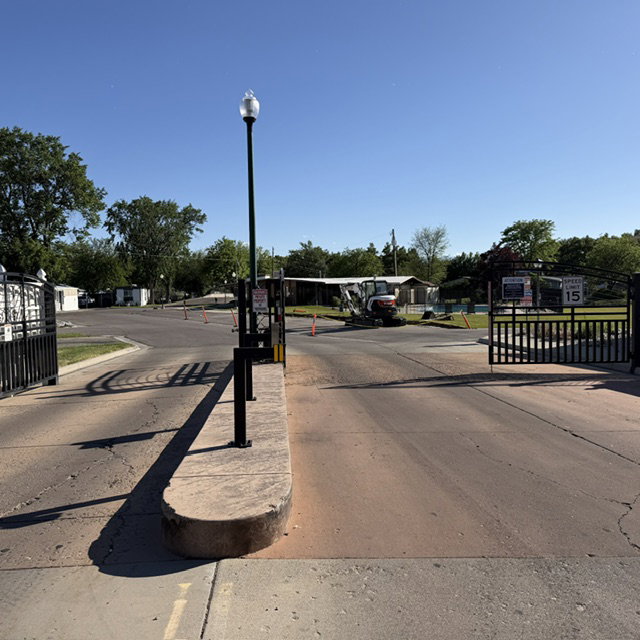 Gated entry with black wrought iron fencing and a central lamppost