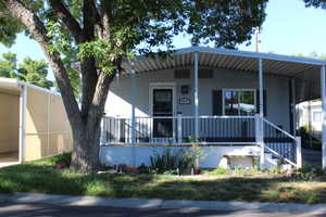 Light gray exterior featuring a covered front porch, white railings, and dark shutters