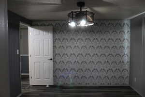 Primary Bedroom with Accent wall featuring grey patterned wallpaper, complemented by grey wood-finish flooring