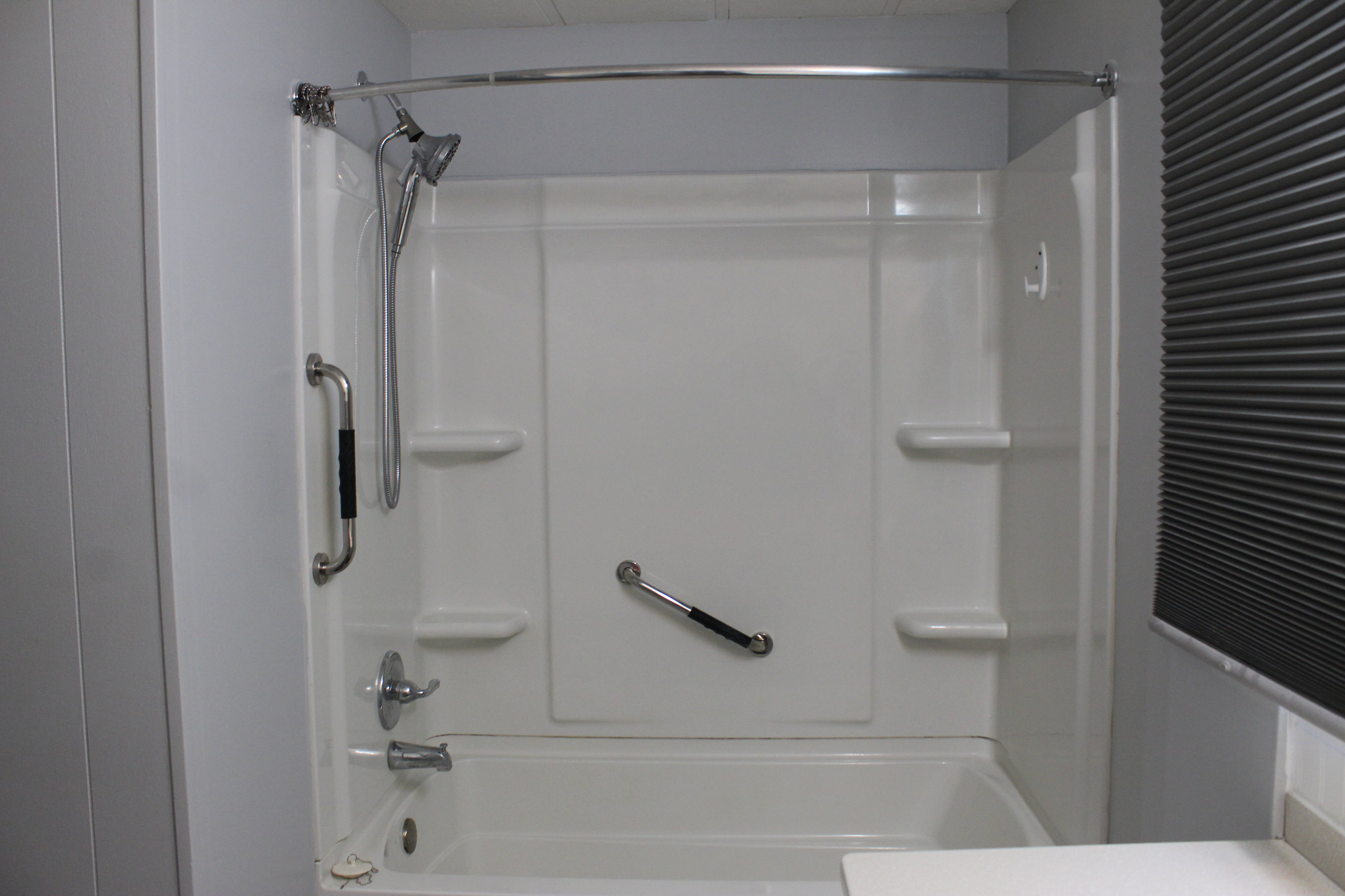 Primary bathroom White acrylic tub and shower combination with chrome fixtures