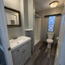 Bathroom featuring a neutral-toned vanity with an integrated sink, polished chrome faucet, and a decorative framed mirror.  this leads into the laundry room