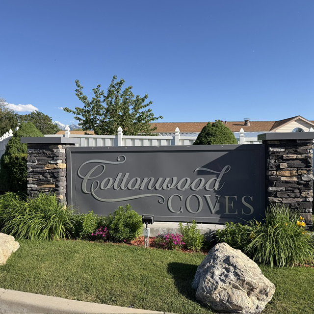 Cottonwood Coves entry monument with stacked stone pillars and a dark grey sign panel