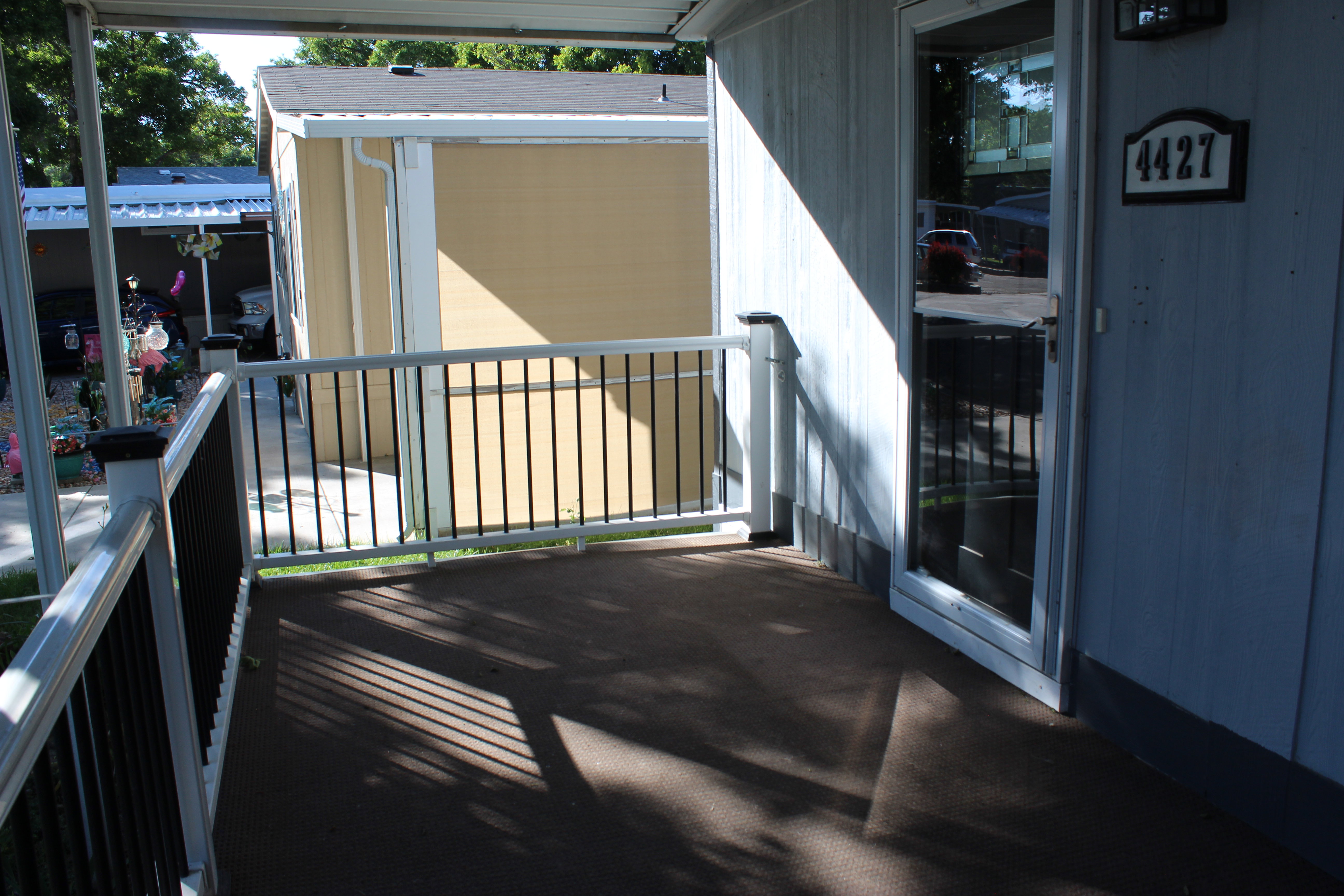 Covered porch with dark flooring, white railing with black balusters, and a storm door.  nice large porch to enjoy coffee with the sunrise or relaxing in the evening.