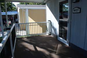 Covered porch with dark flooring, white railing with black balusters, and a storm door.  nice large porch to enjoy coffee with the sunrise or relaxing in the evening.