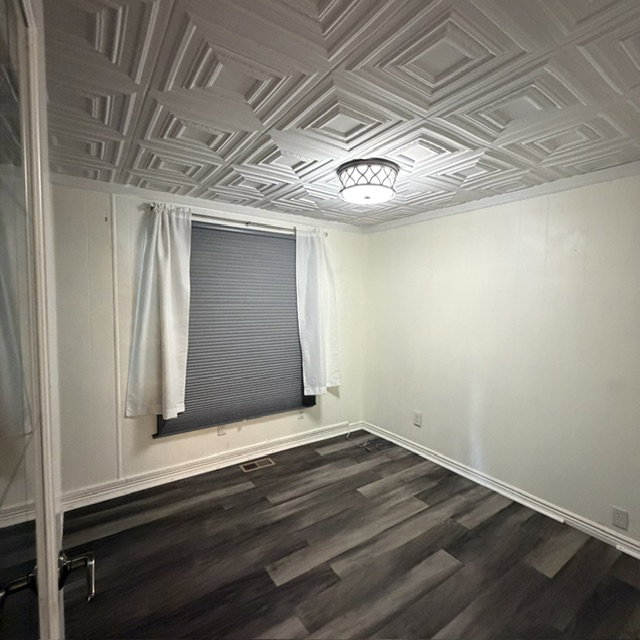 1st bedroom. Room featuring a detailed coffered ceiling, a flush-mount ceiling light fixture, and wood-finish flooring, glass door, window coverings.