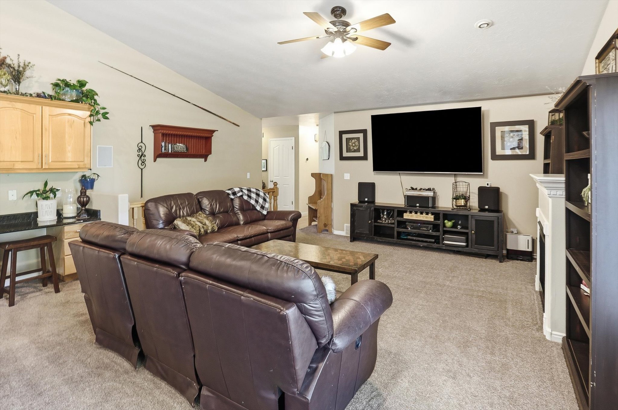 Spacious living area featuring vaulted ceilings, a ceiling fan, and carpeted flooring