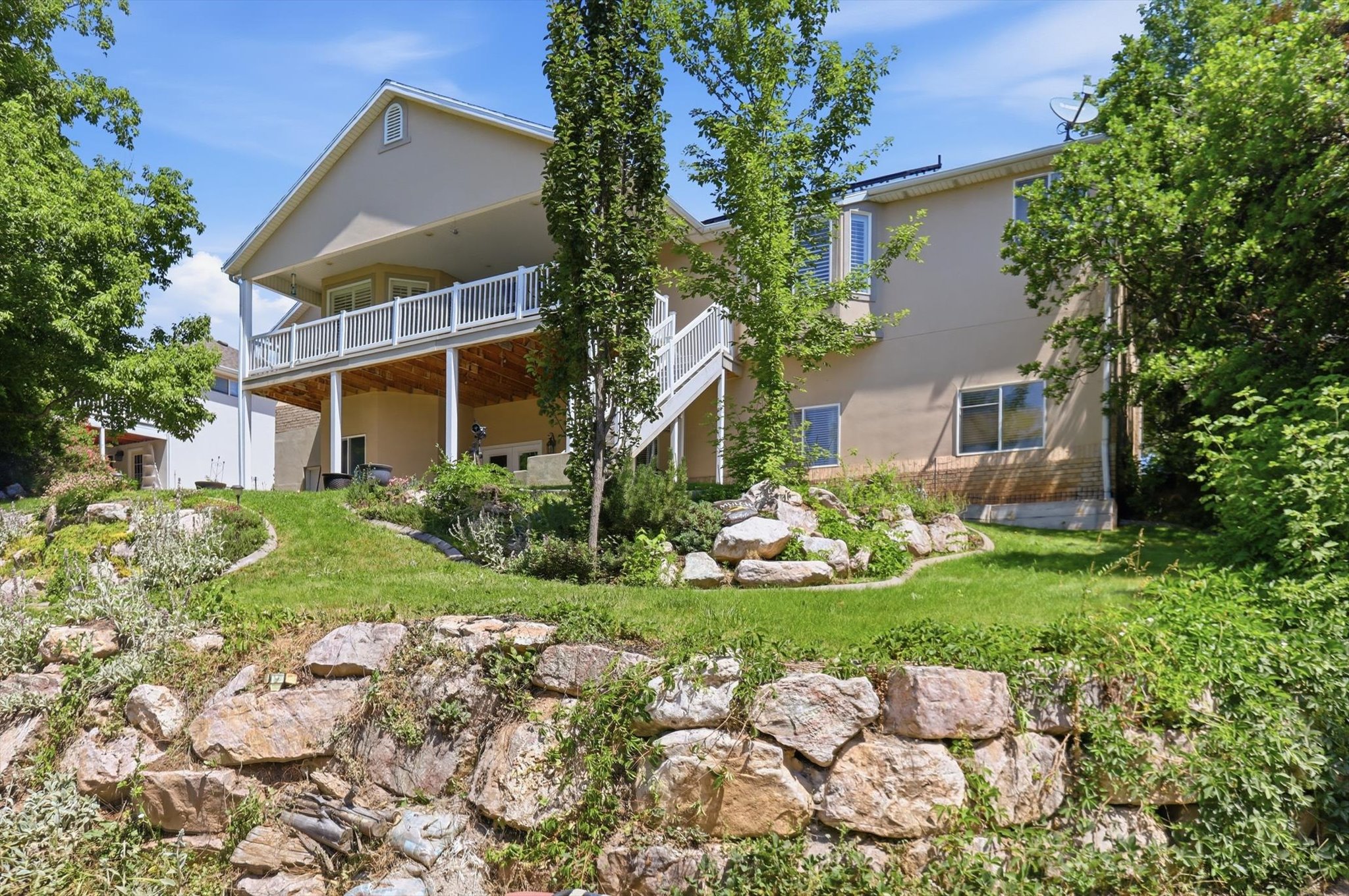 Multi-story residence featuring a second-level deck with white railing, supported by columns and offering covered patio space below