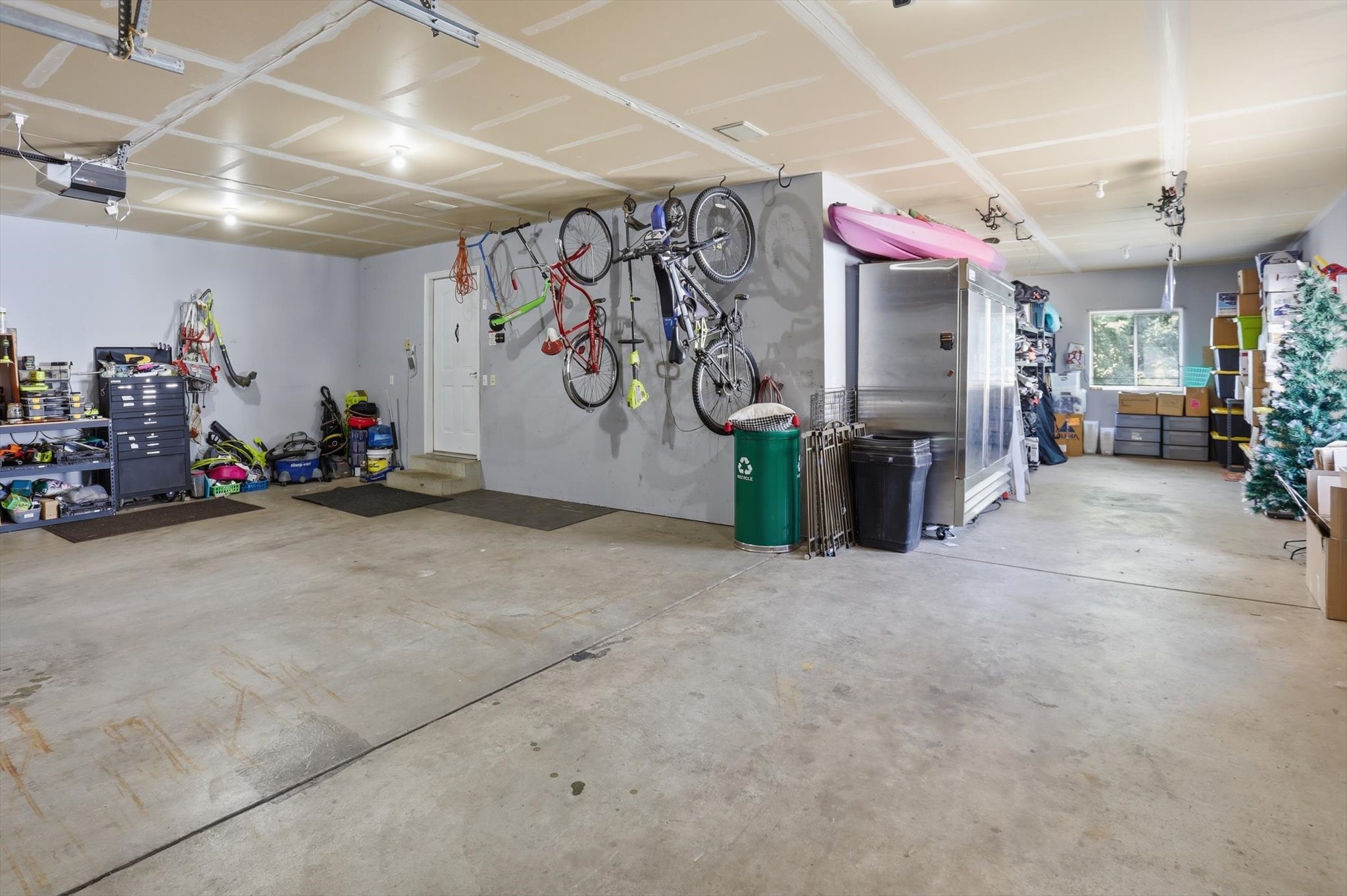 Spacious garage with multiple overhead garage doors, exposed ceiling joists, and concrete flooring