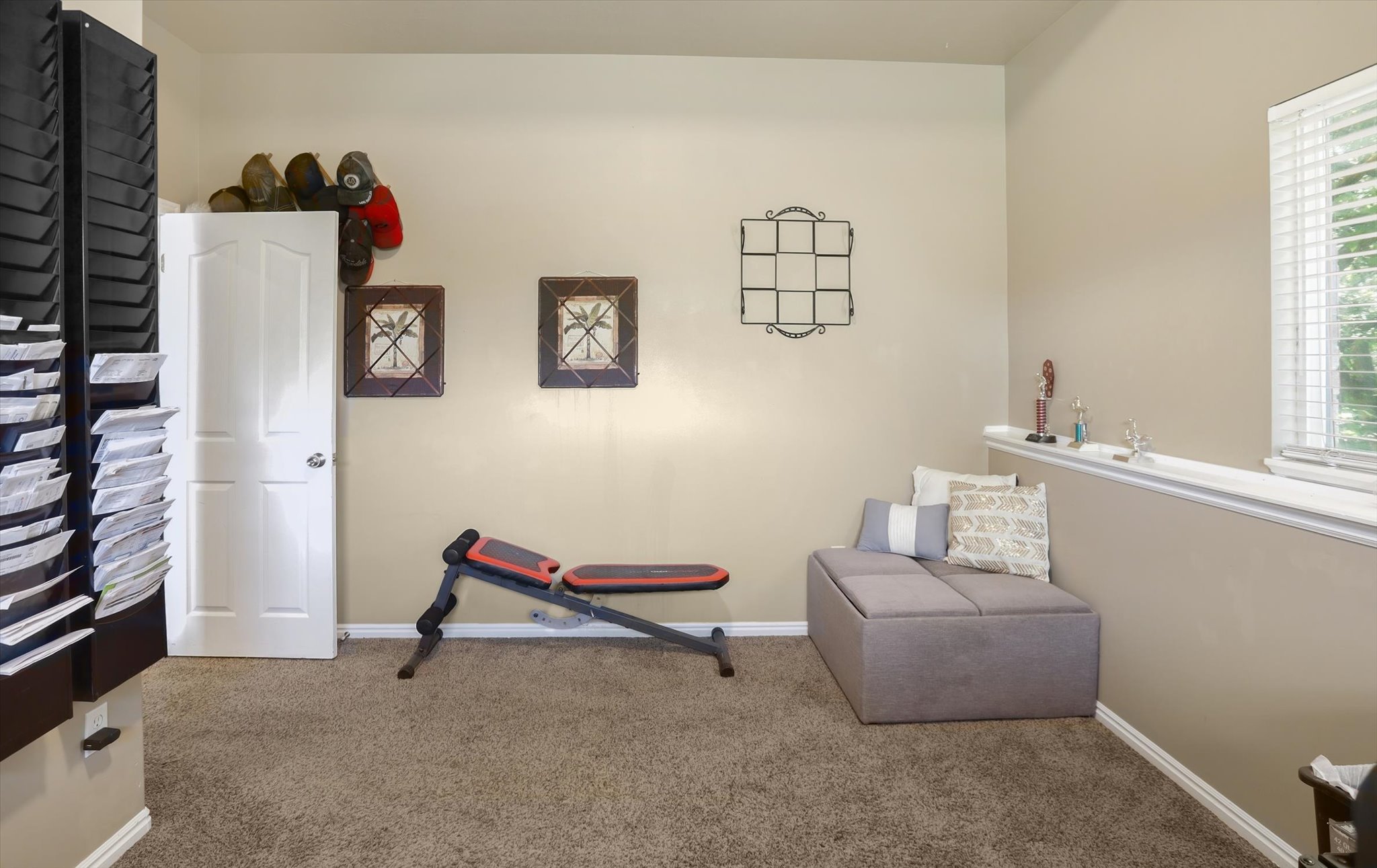 Carpeted interior space featuring a white paneled door, a built-in half-wall ledge, and a window with white blinds