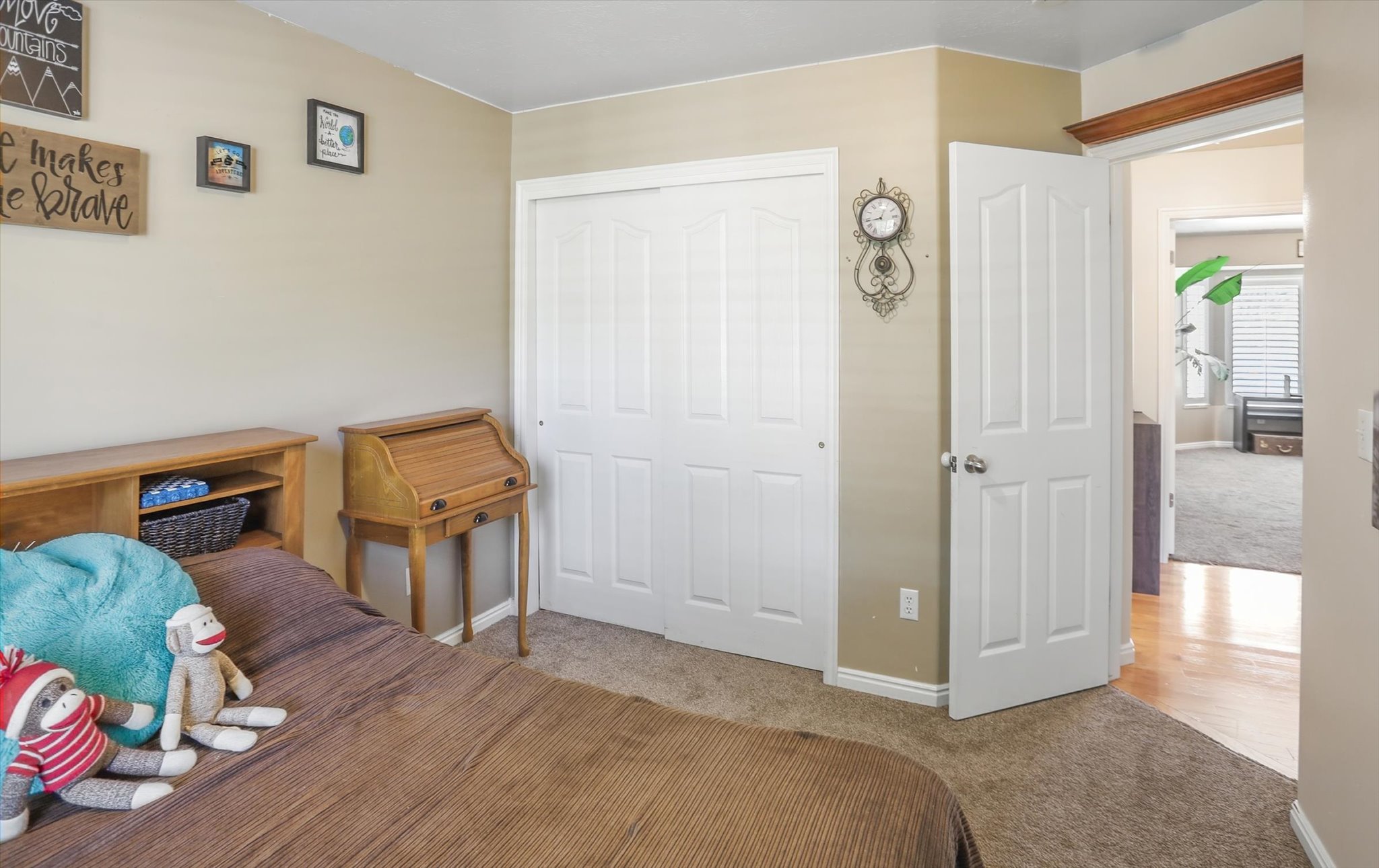 Bedroom featuring neutral wall paint, carpet flooring, a white bi-fold closet door, and a white paneled door opening to wood-finish flooring