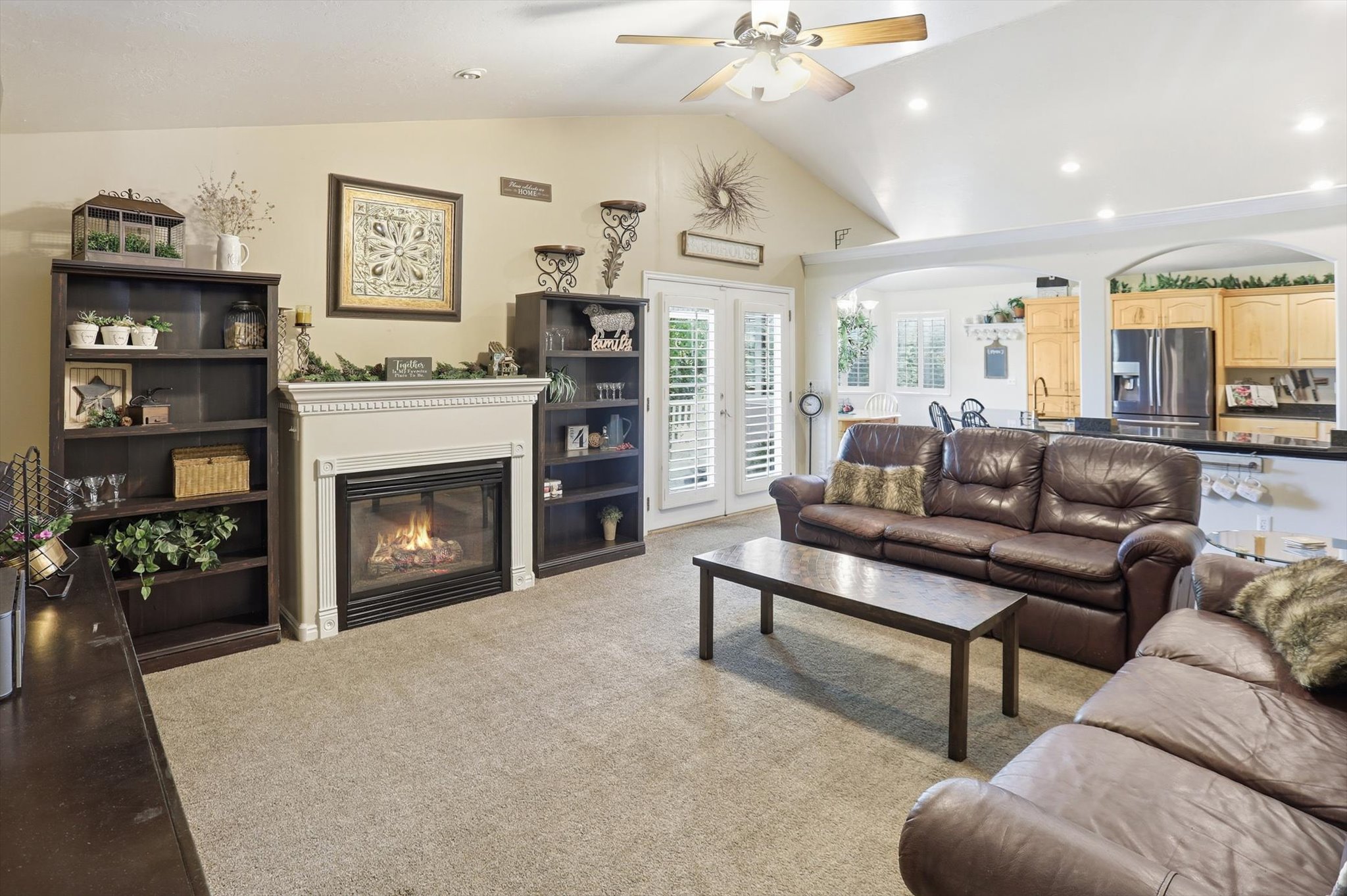 Vaulted ceiling with a ceiling fan, recessed lighting, and a fireplace with a mantel