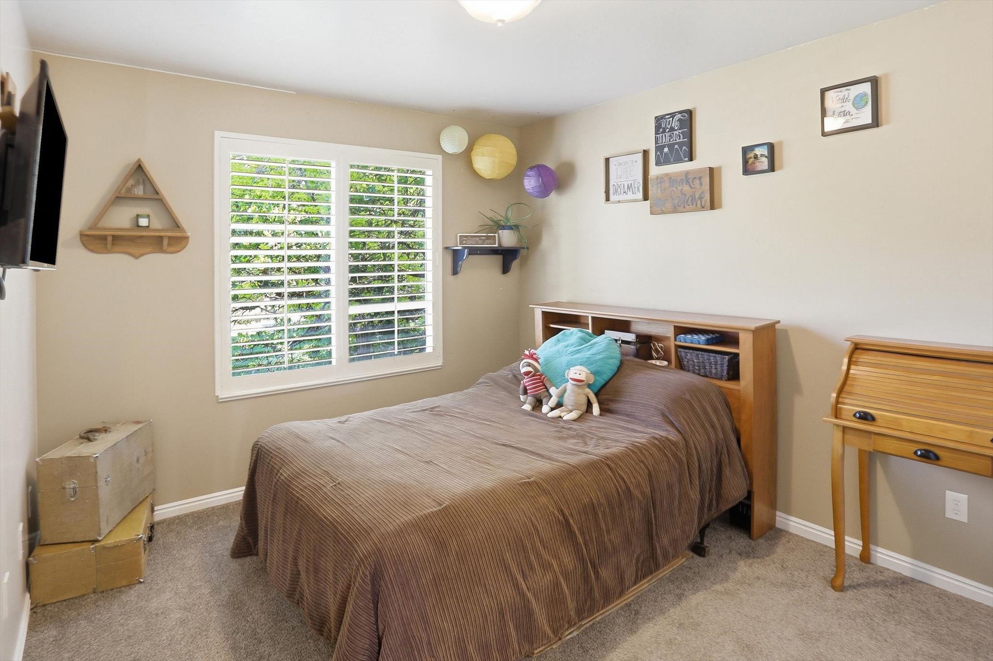Bedroom featuring a large window with white plantation shutters, neutral wall paint, and gray carpet