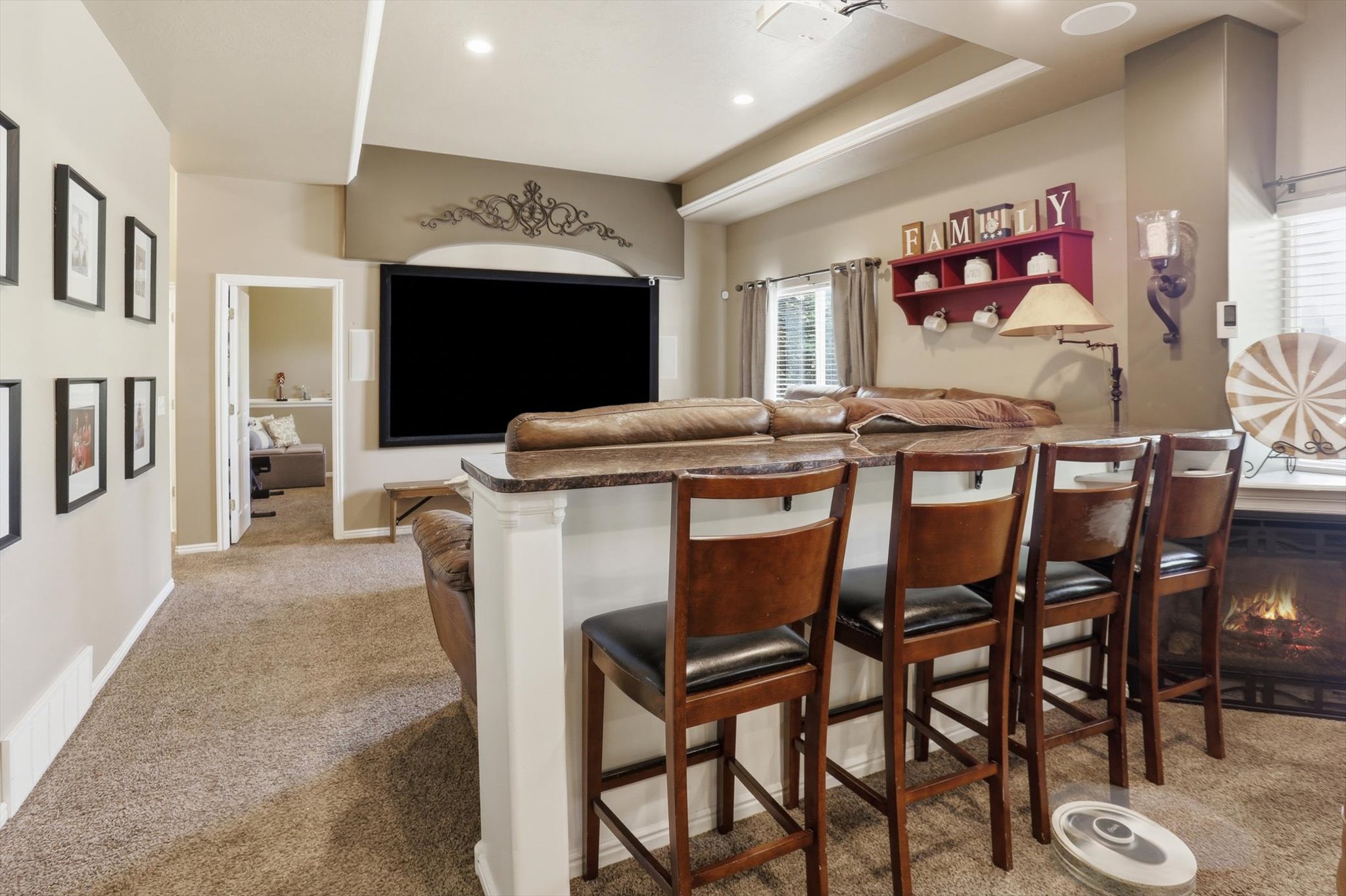 Entertainment area featuring a large screen, integrated fireplace, and a counter with seating for four