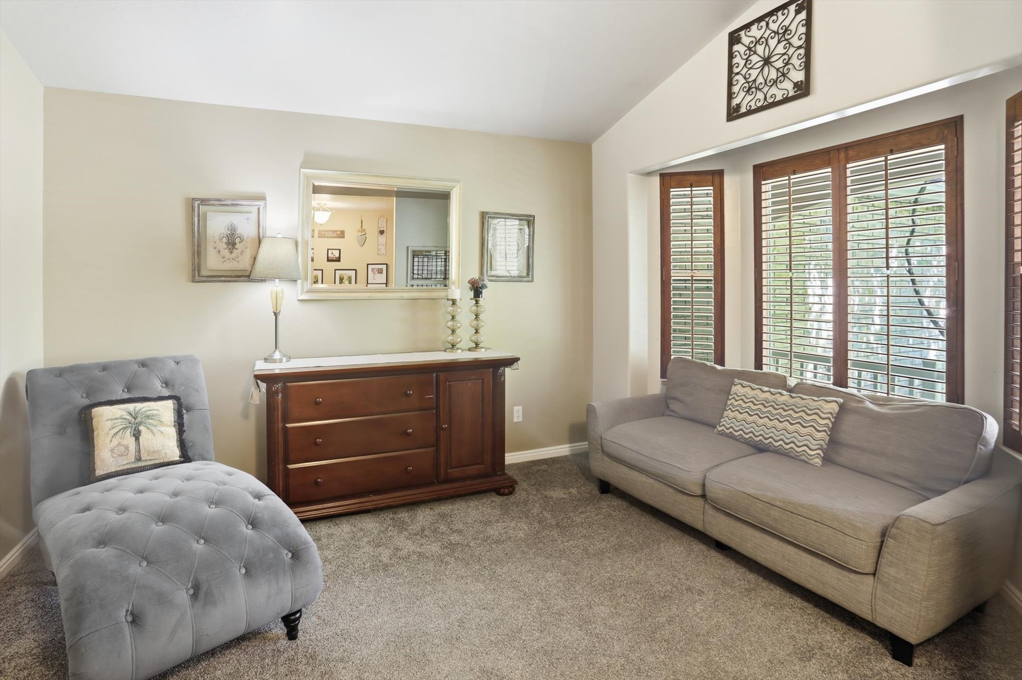 Vaulted ceilings complement a bay window with natural wood plantation shutters