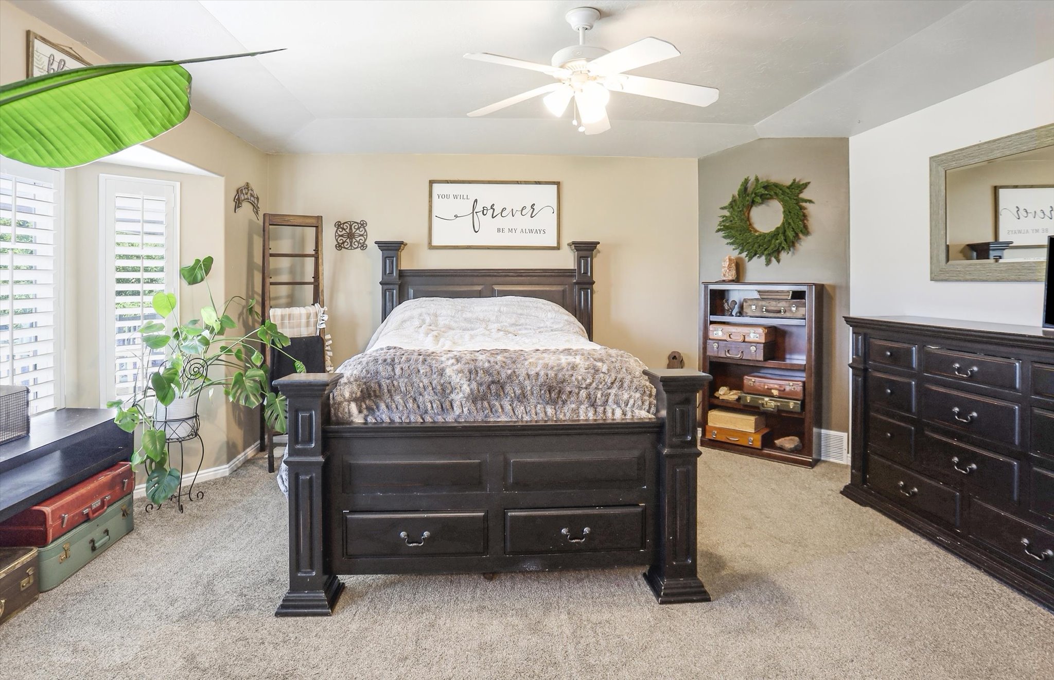 Carpeted interior space featuring a ceiling fan, bay window with plantation shutters, window seat with storage, and a built-in bookshelf