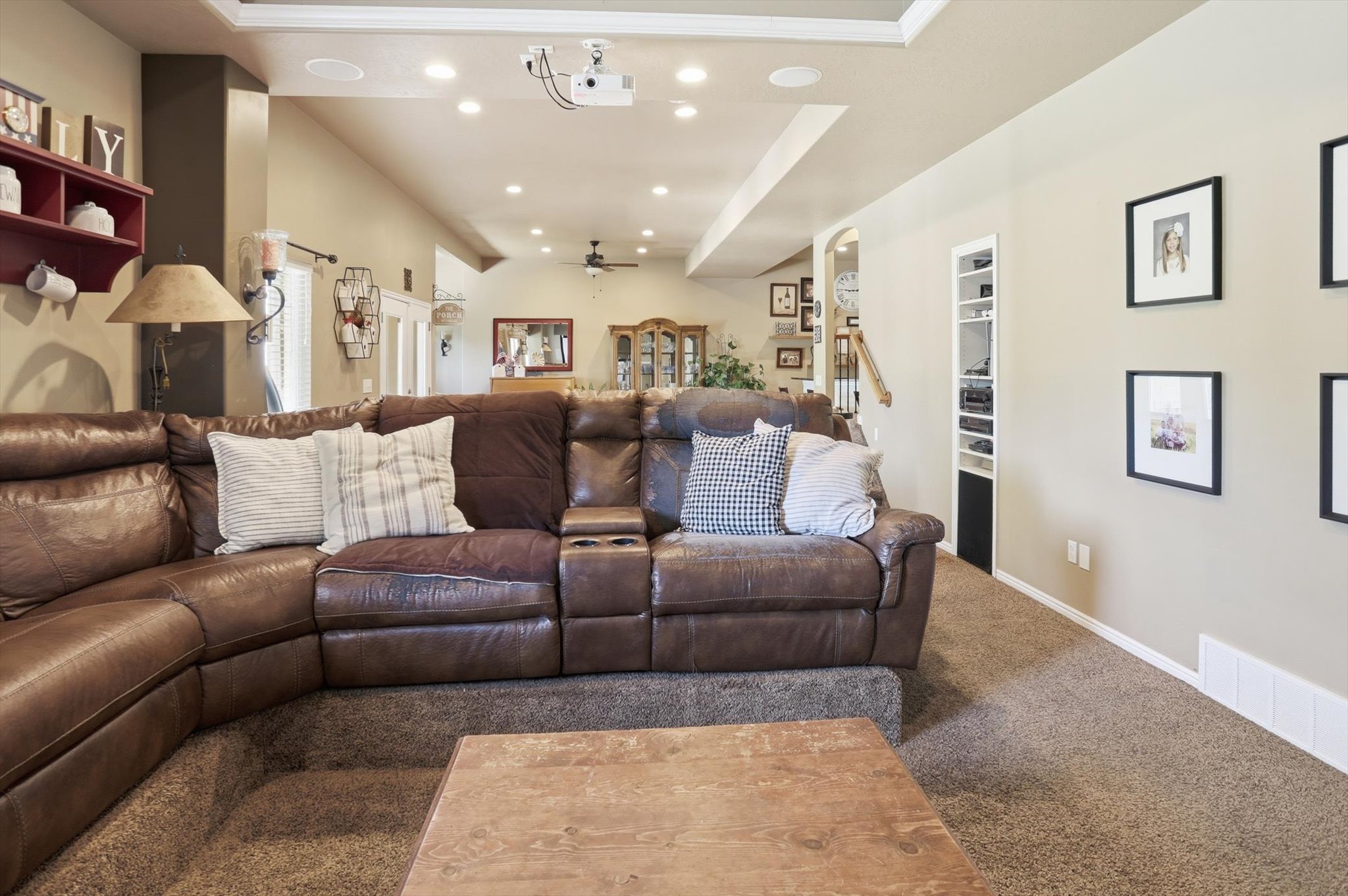Plush carpeted media room featuring recessed ceiling lighting, a built-in projector, and a ceiling-mounted speaker system