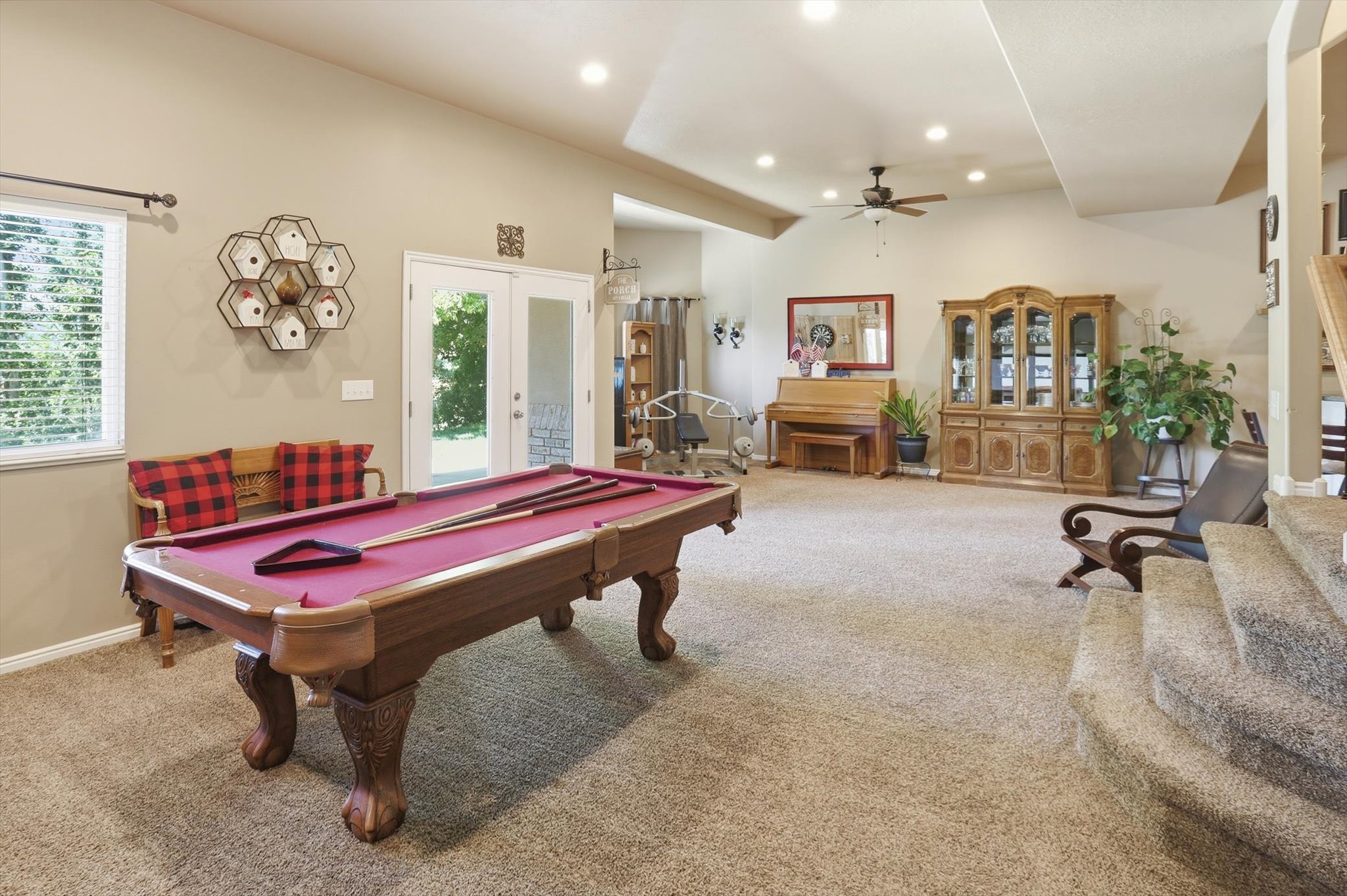 Spacious recreation room featuring a neutral carpet, vaulted ceiling, recessed lighting, and french doors