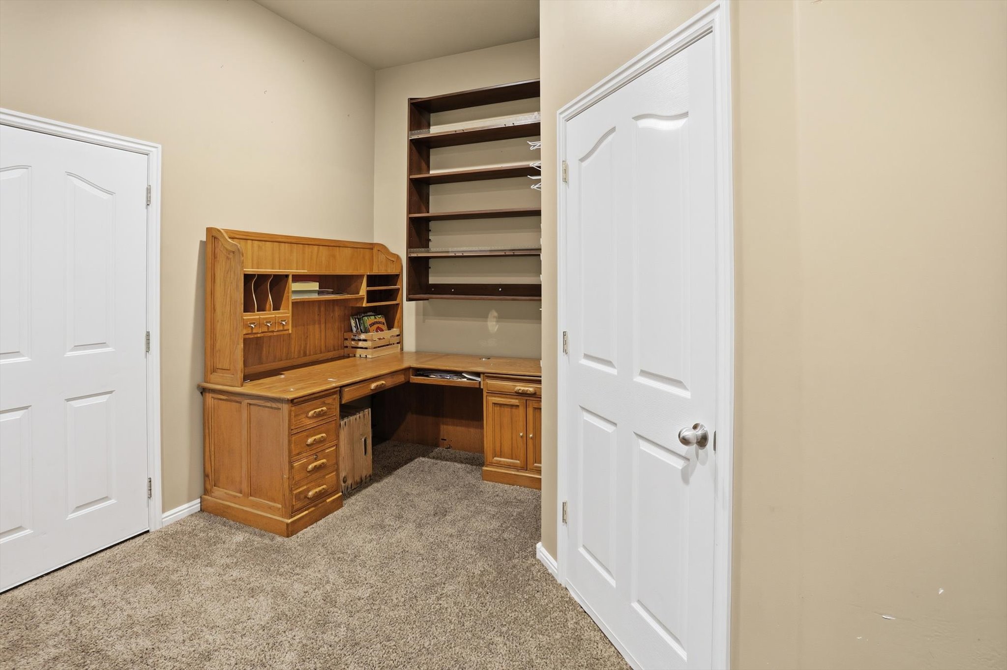 Built-in shelving unit with multiple tiers, carpeted flooring, and neutral wall tones