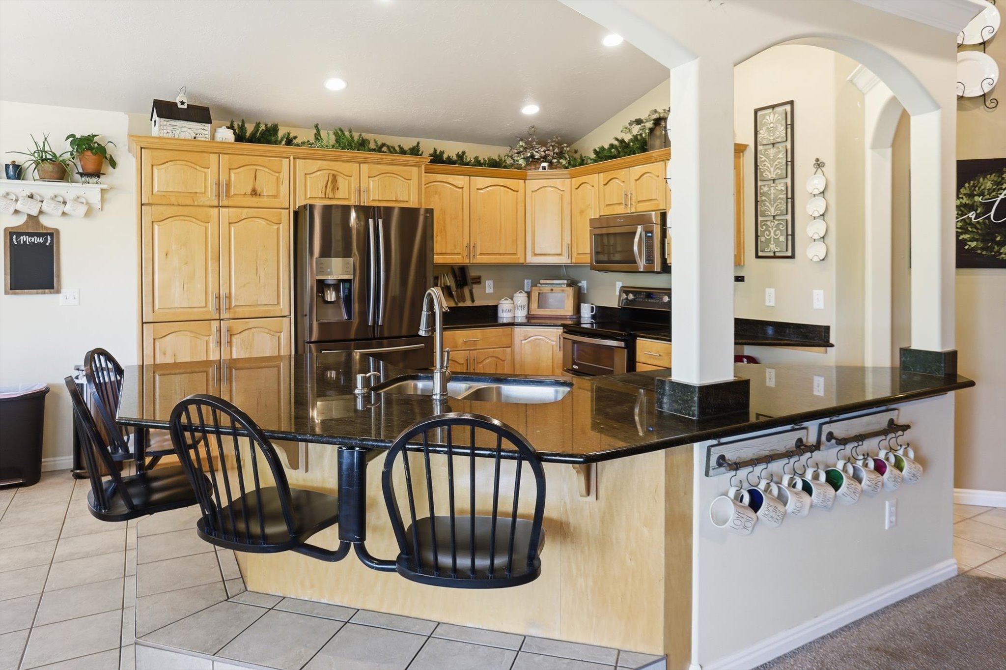 Kitchen featuring light wood cabinetry, stainless steel appliances, and dark granite countertops