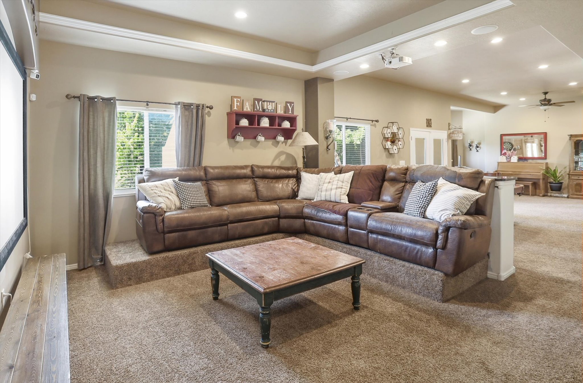 Carpeted entertainment space featuring a projector, recessed lighting, and a tray ceiling