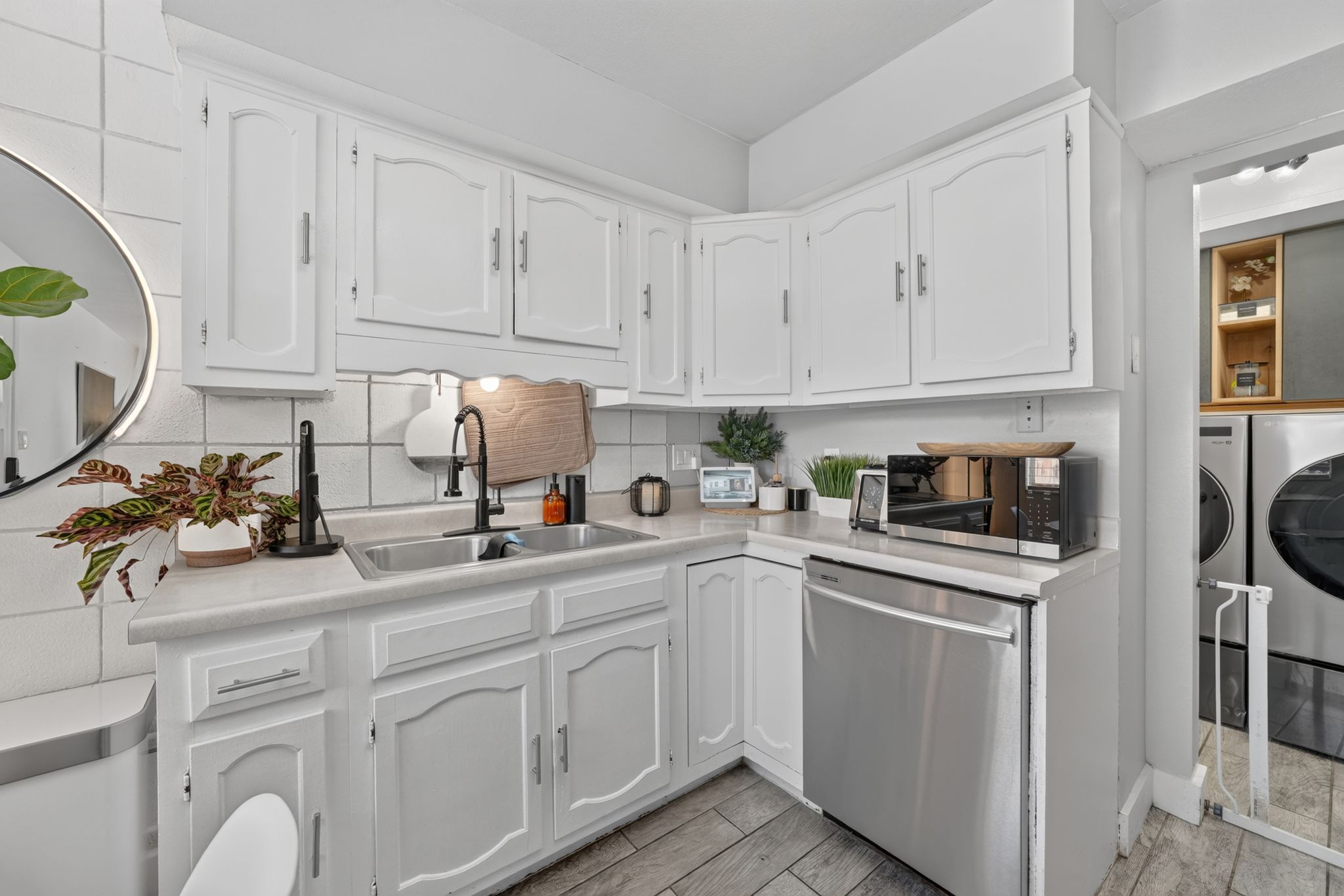 Kitchenette with white cabinetry, light-toned countertops, and a tile backsplash