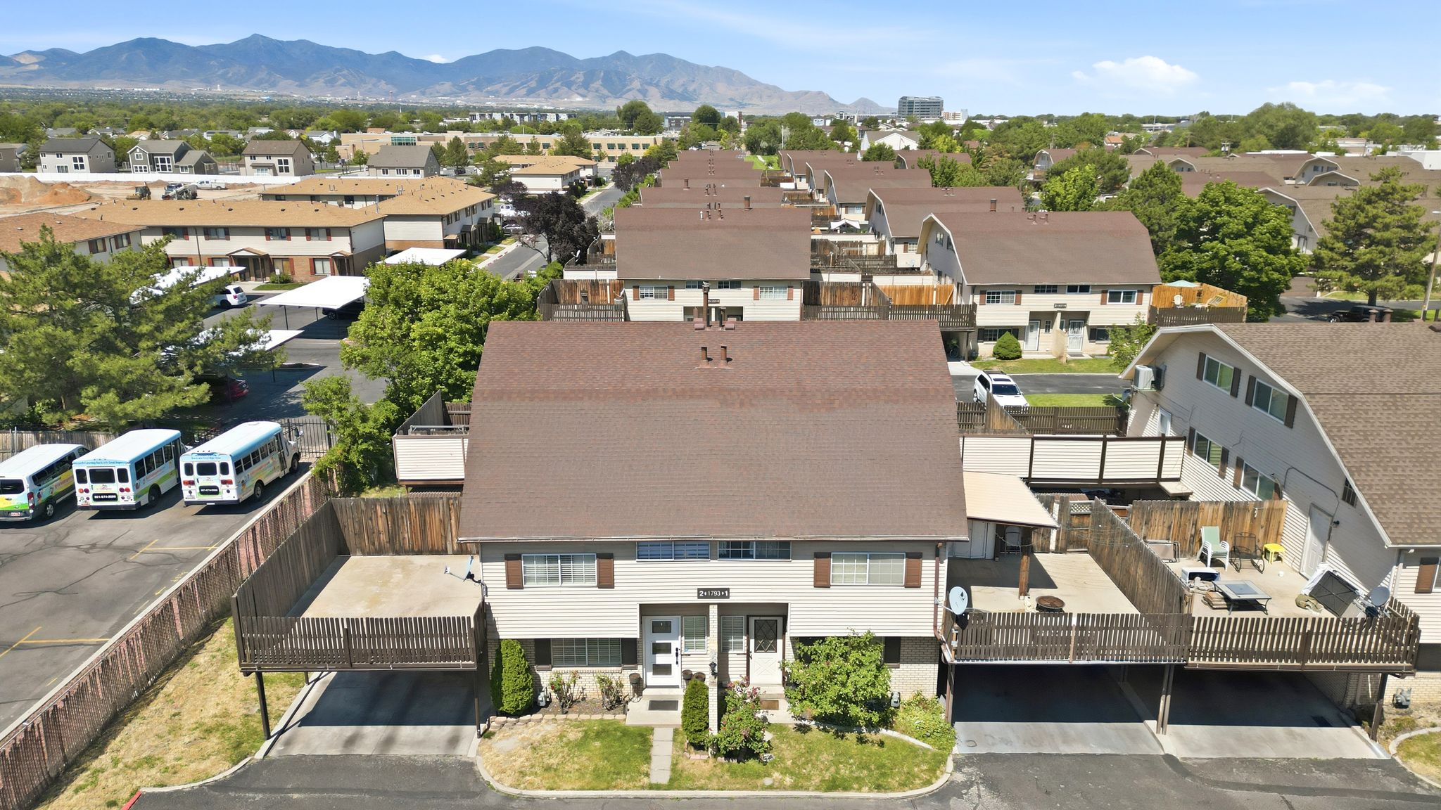 Multi-unit residential structure featuring a brown shingle roof and light-colored siding