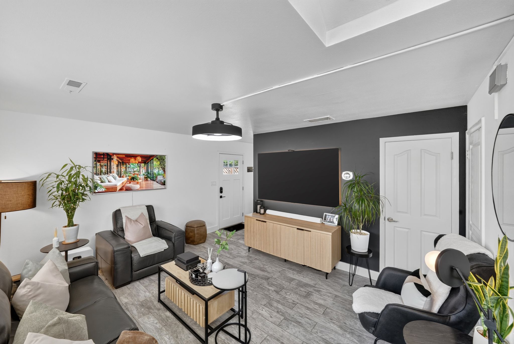 Living area featuring light wood-finish flooring, white walls, and a contrasting accent wall