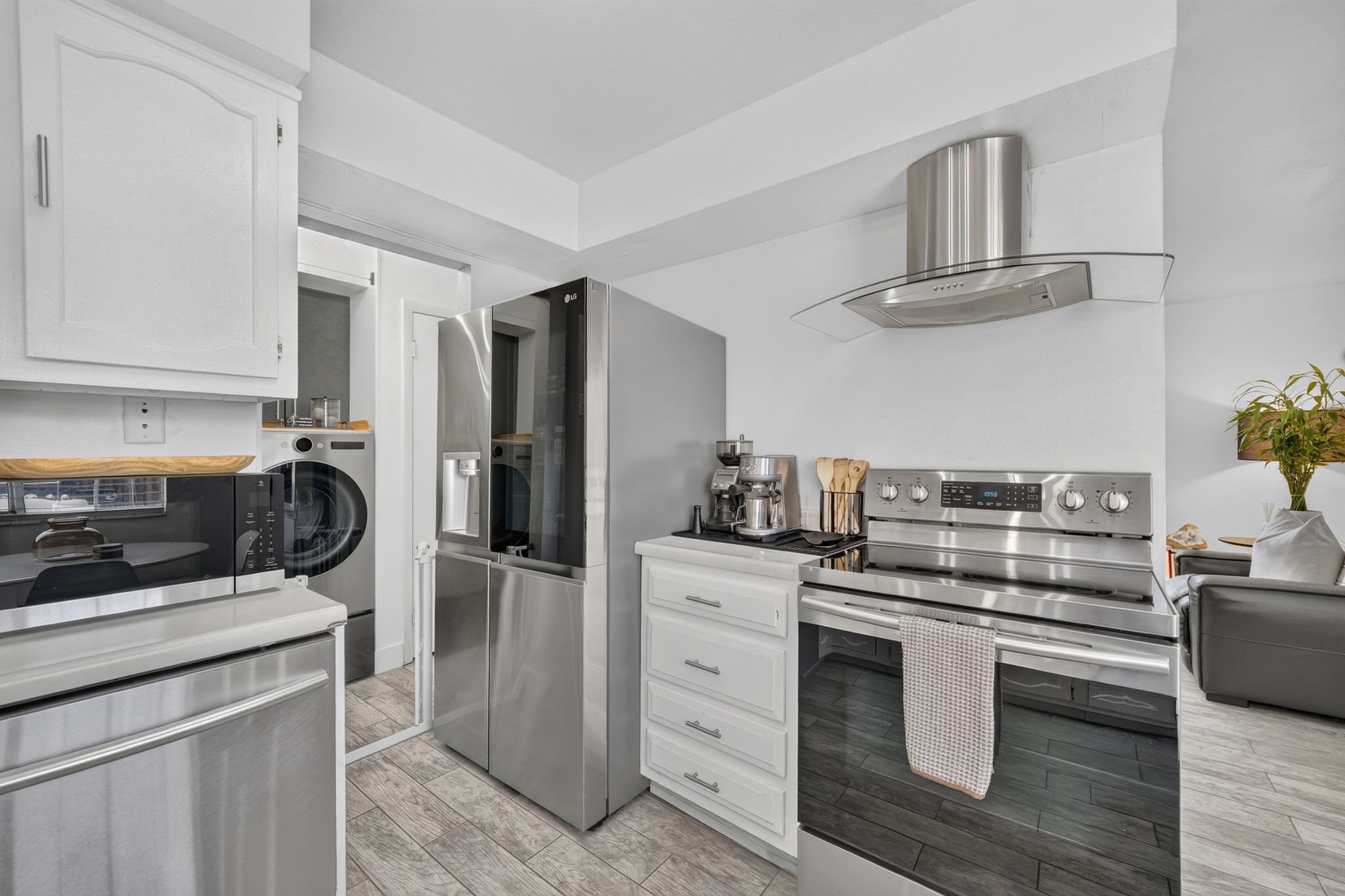 White kitchen cabinetry with stainless steel appliances, including a refrigerator, range, and microwave
