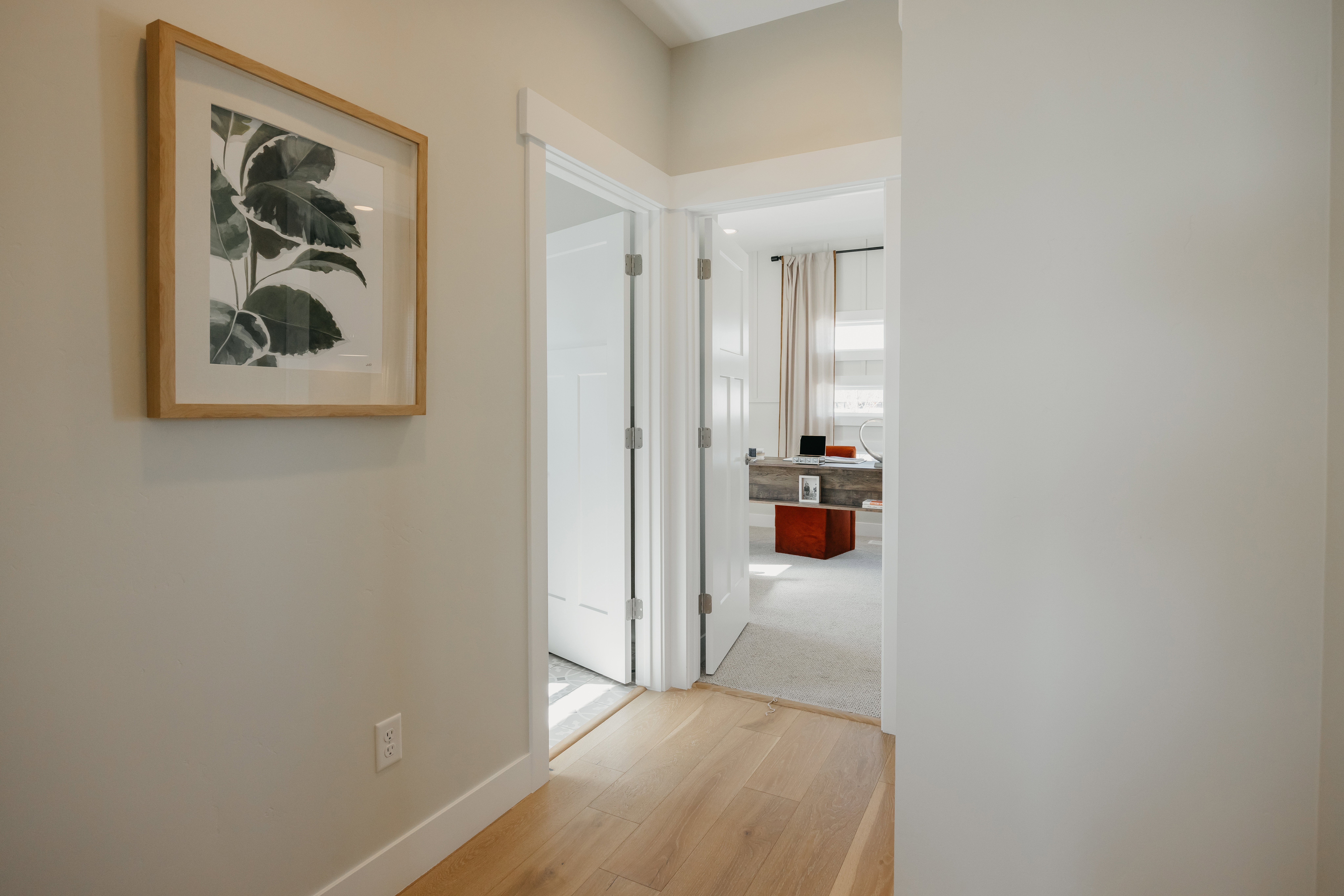 Hallway featuring light wood-finish flooring, white baseboards, and neutral wall paint
