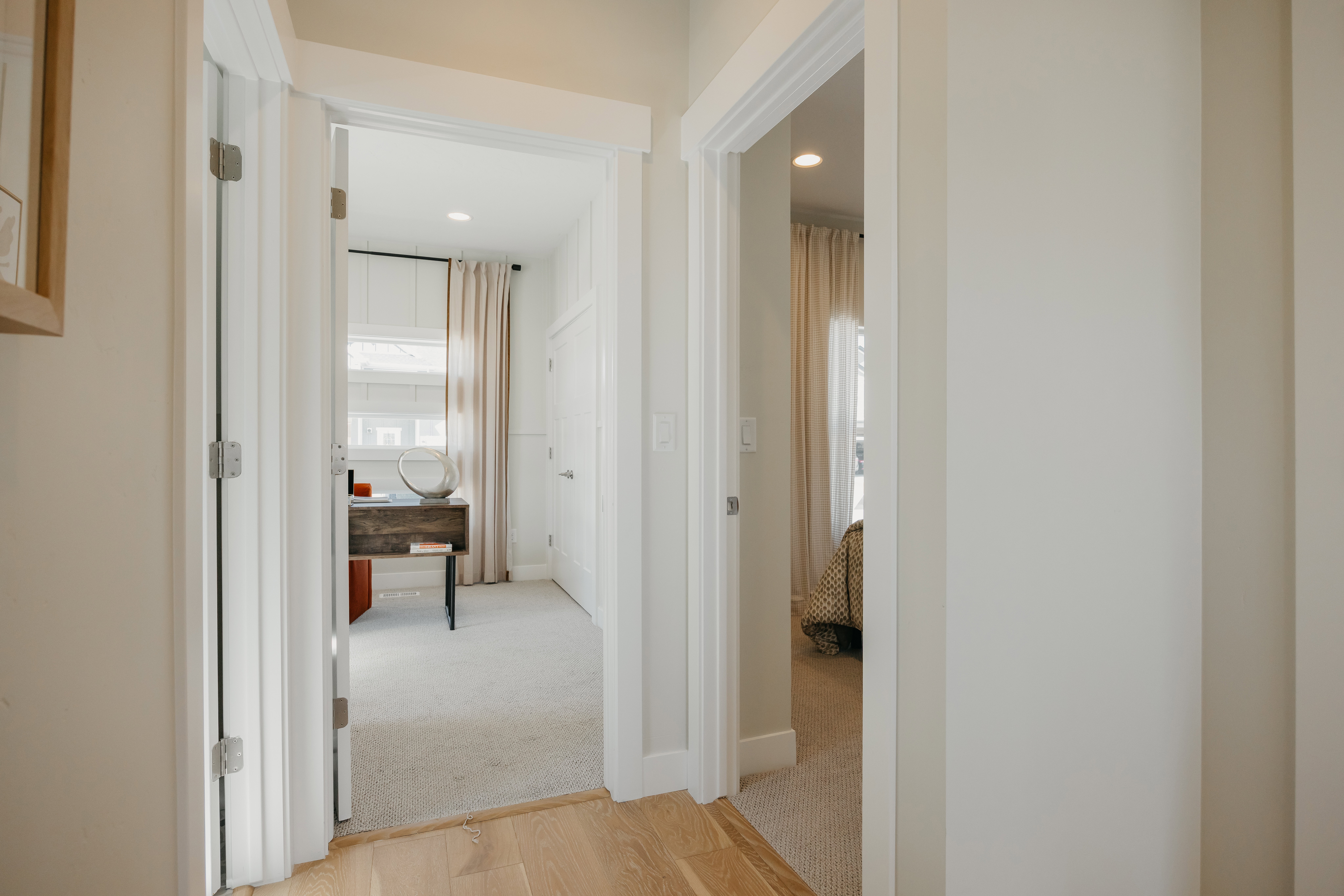 Hallway featuring light wood-finish flooring, white trim, and neutral wall paint
