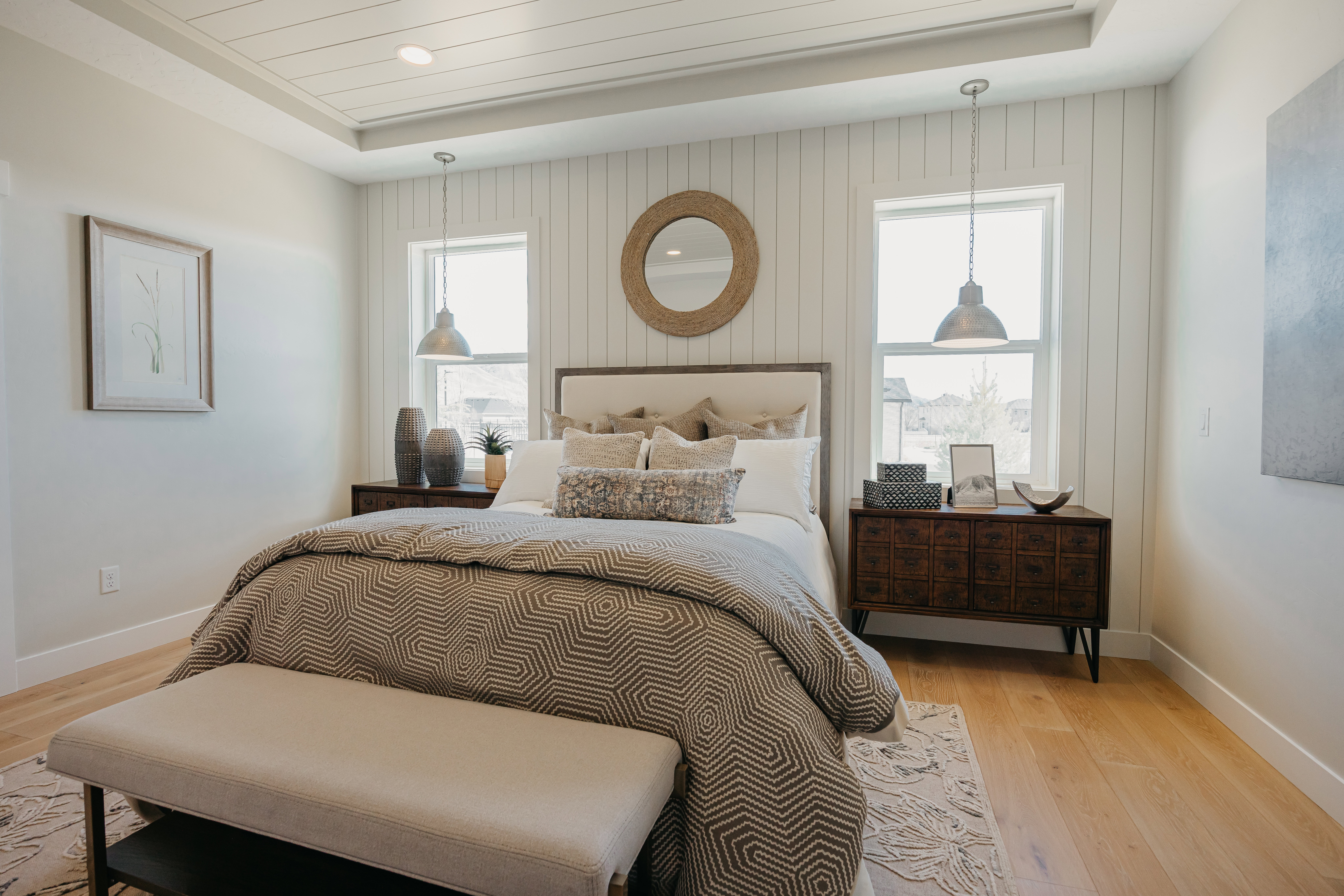 Recessed ceiling with plank detailing, vertical shiplap accent wall, wood-finish flooring, two large windows, and pendant lighting fixtures