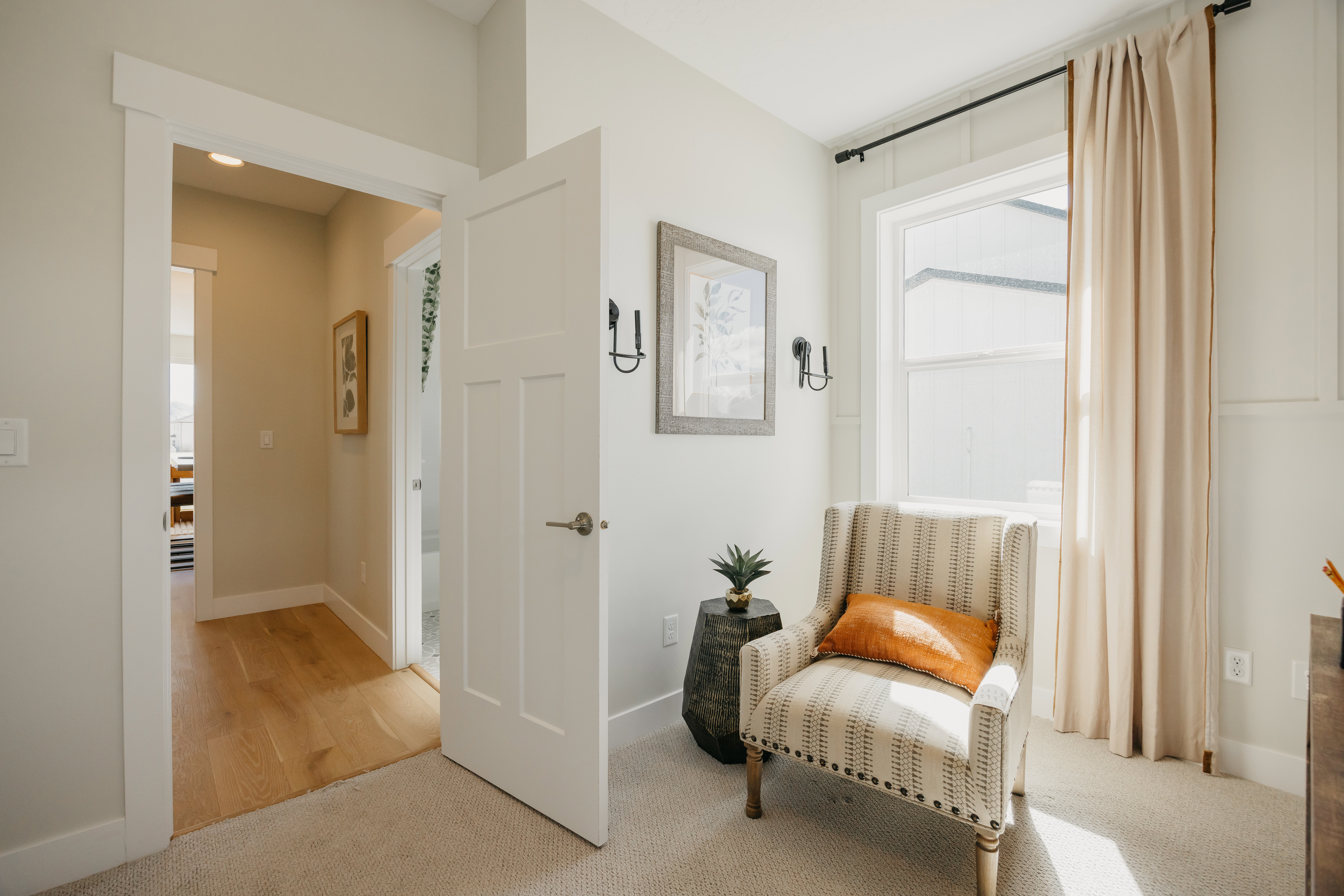 Bright room featuring wall paneling, a large window with drapes, and sconce lighting