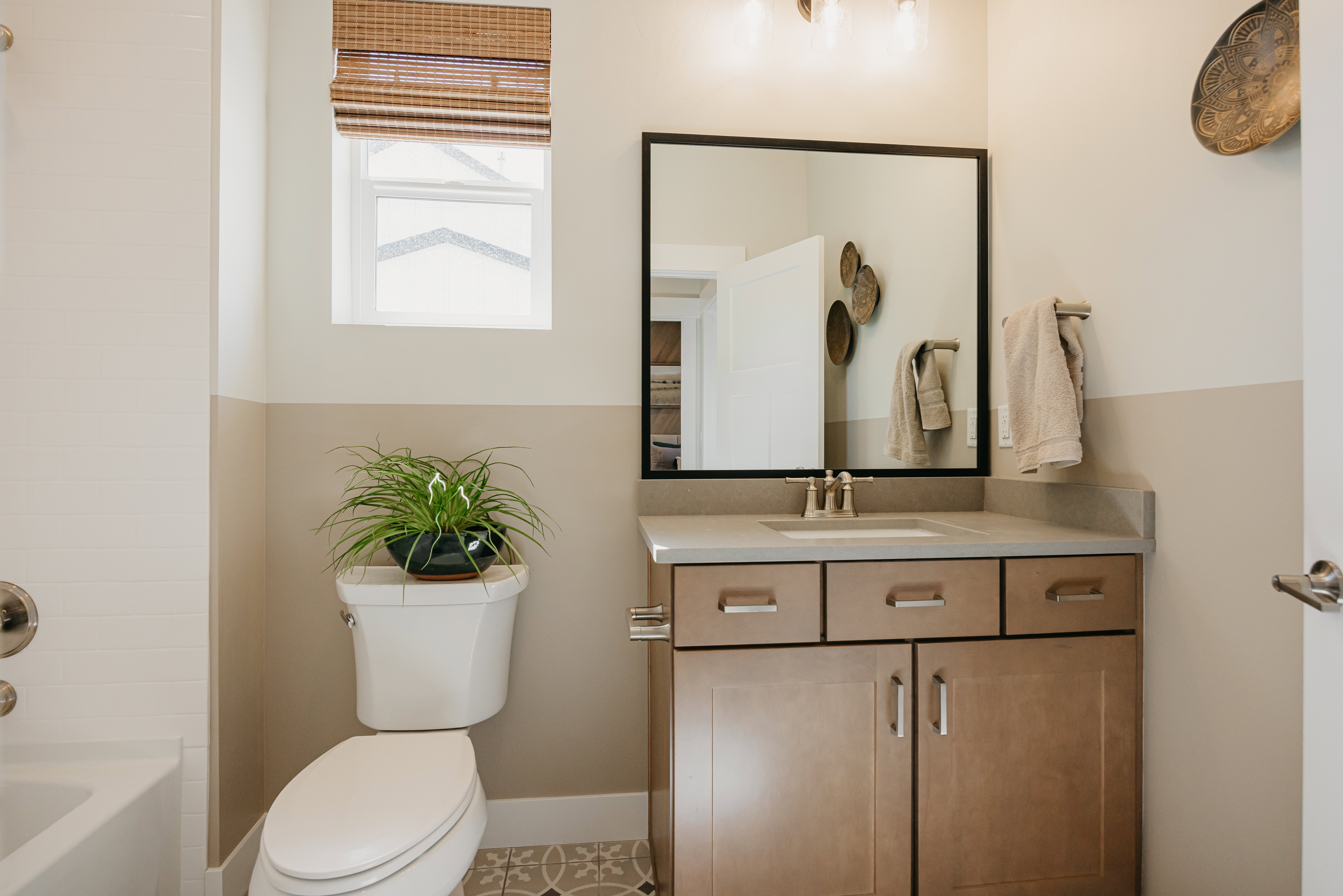 Bathroom featuring a light wood-finish vanity with a light-toned countertop, an undermount sink, and a framed mirror