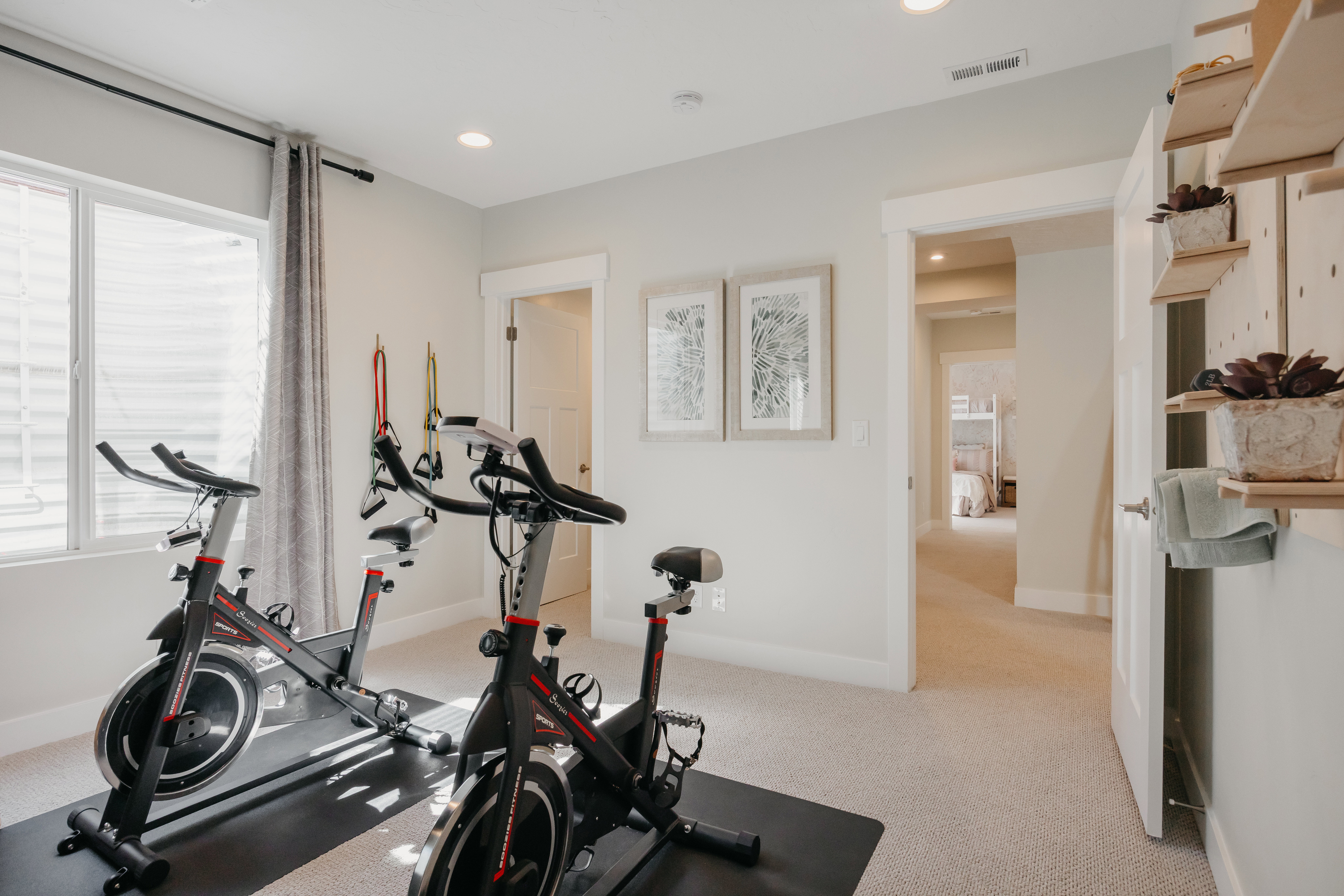 Dedicated exercise space featuring a large window with privacy blinds and soft window treatments, recessed lighting, and wall-mounted shelving
