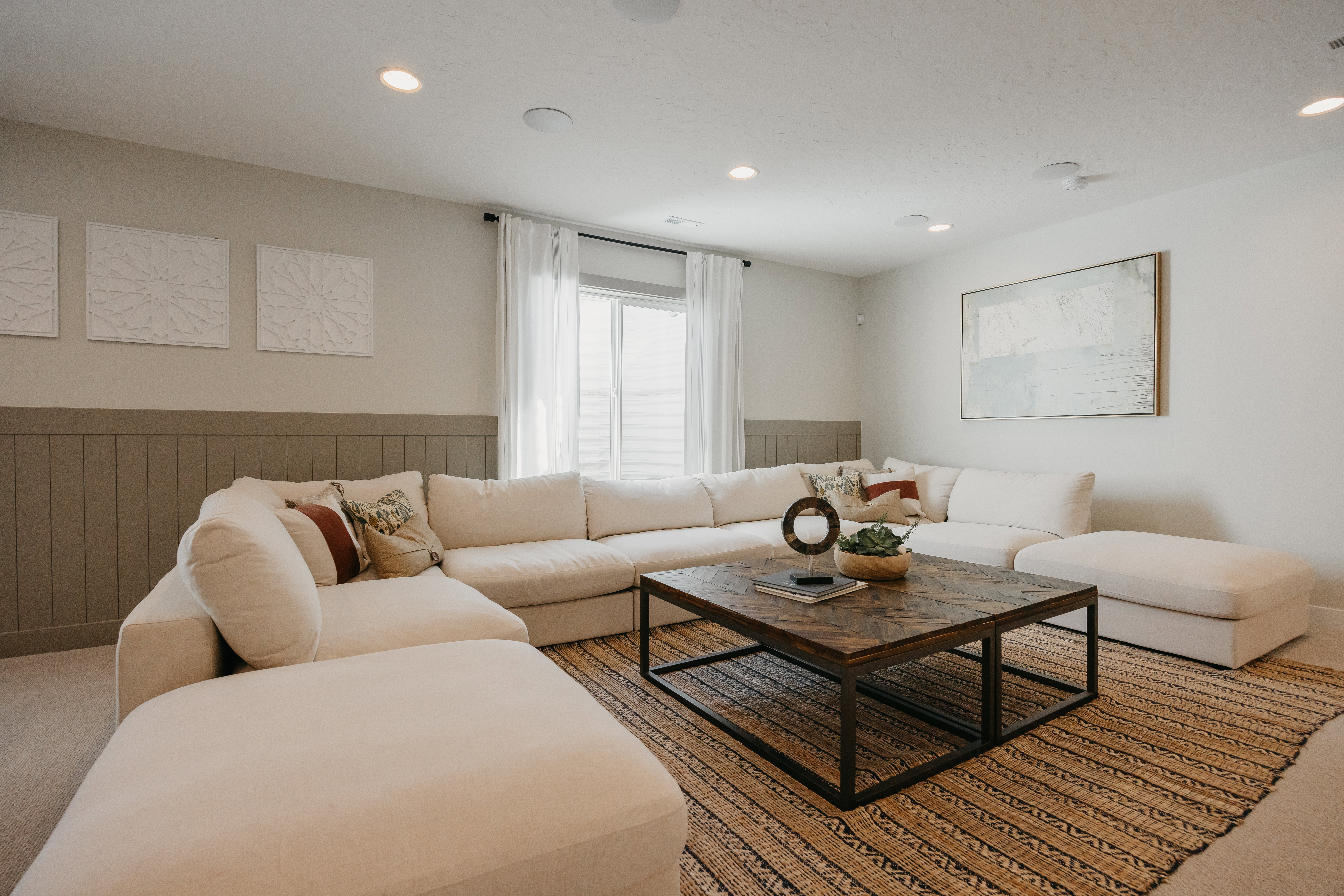 Spacious living area featuring board and batten wainscoting, recessed lighting, and a large window with sheer drapery