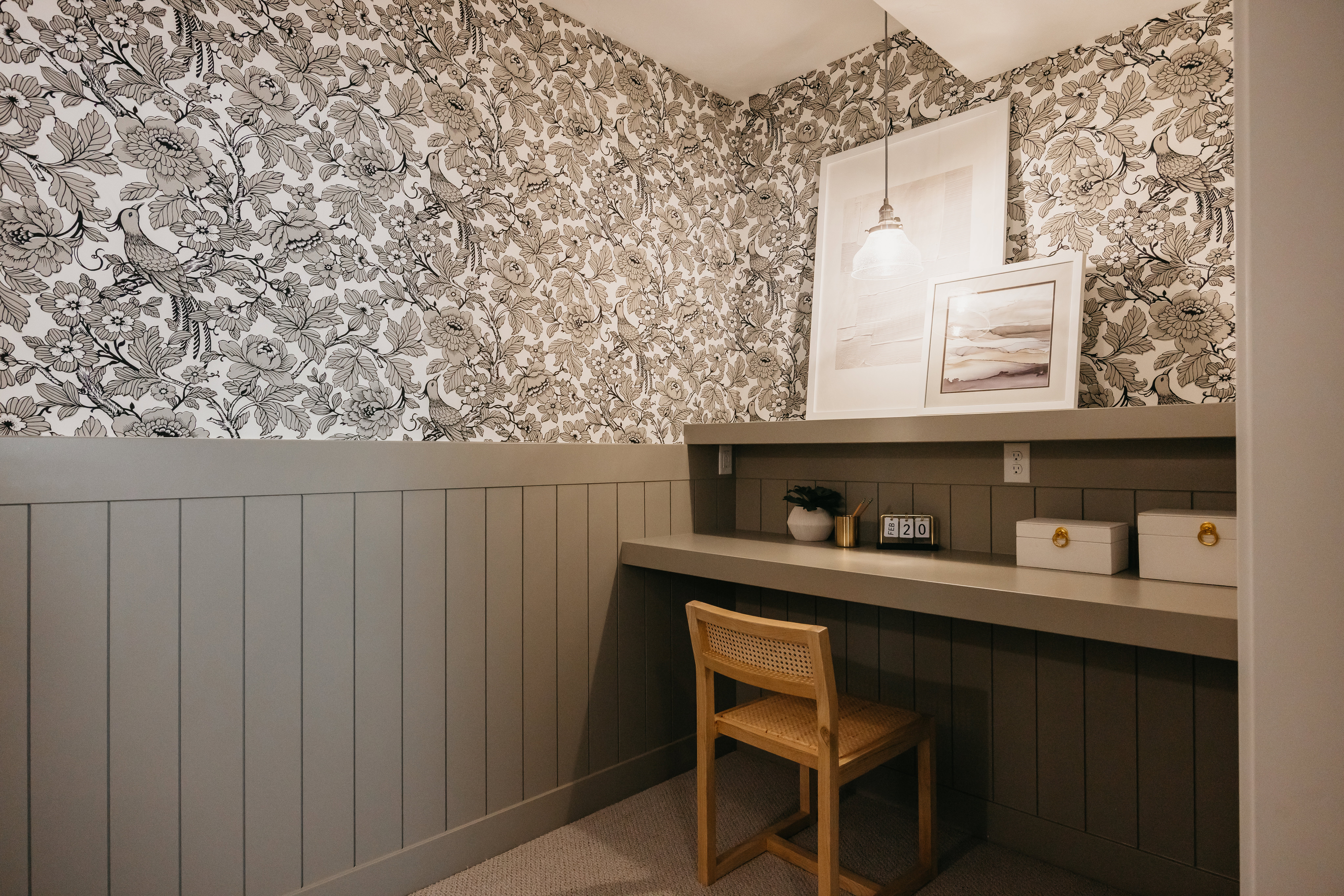 Built-in desk area featuring a matte gray countertop, beadboard wainscoting, and patterned wallpaper