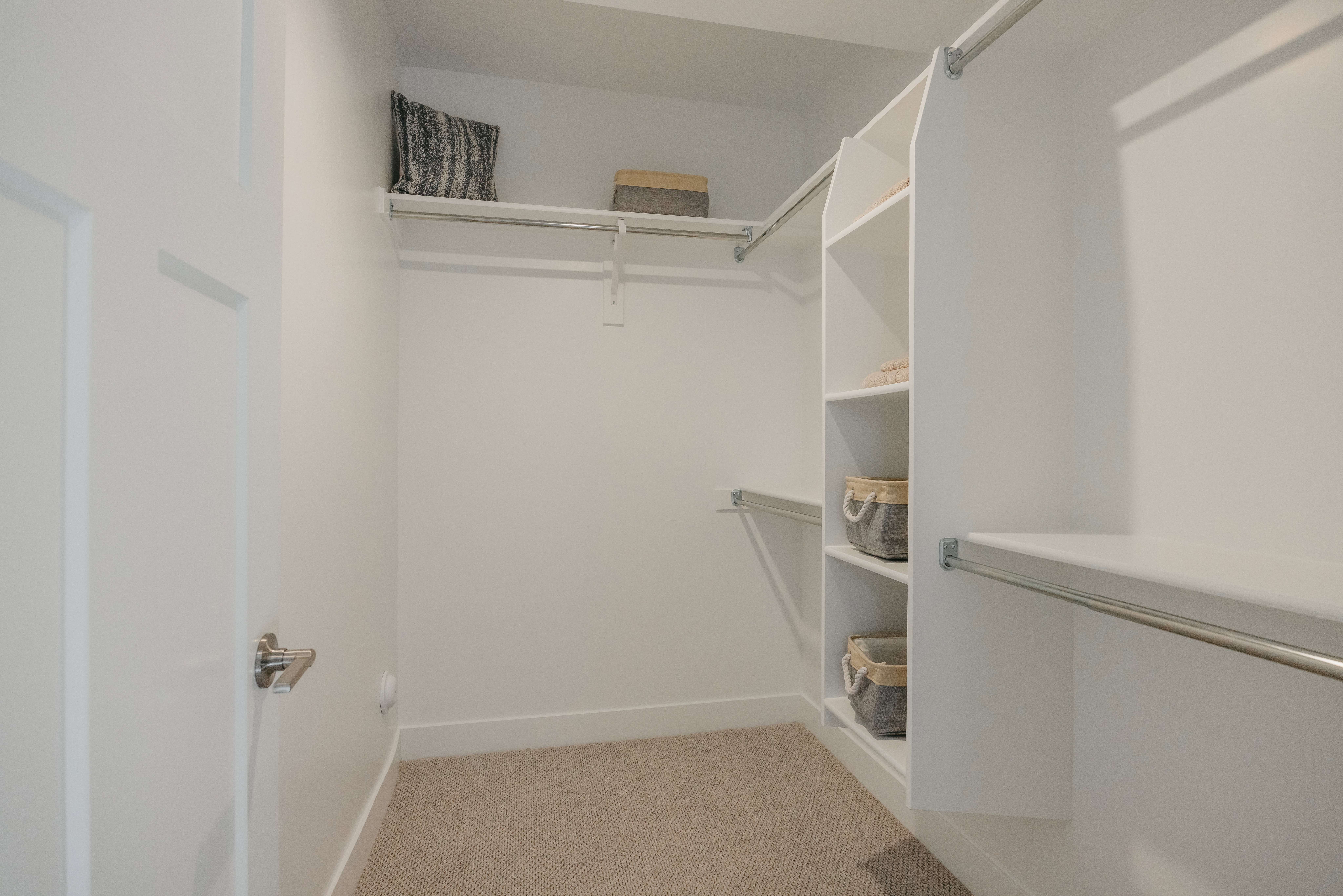 Walk-in closet featuring built-in shelving, multiple hanging rods, and neutral-toned carpeting