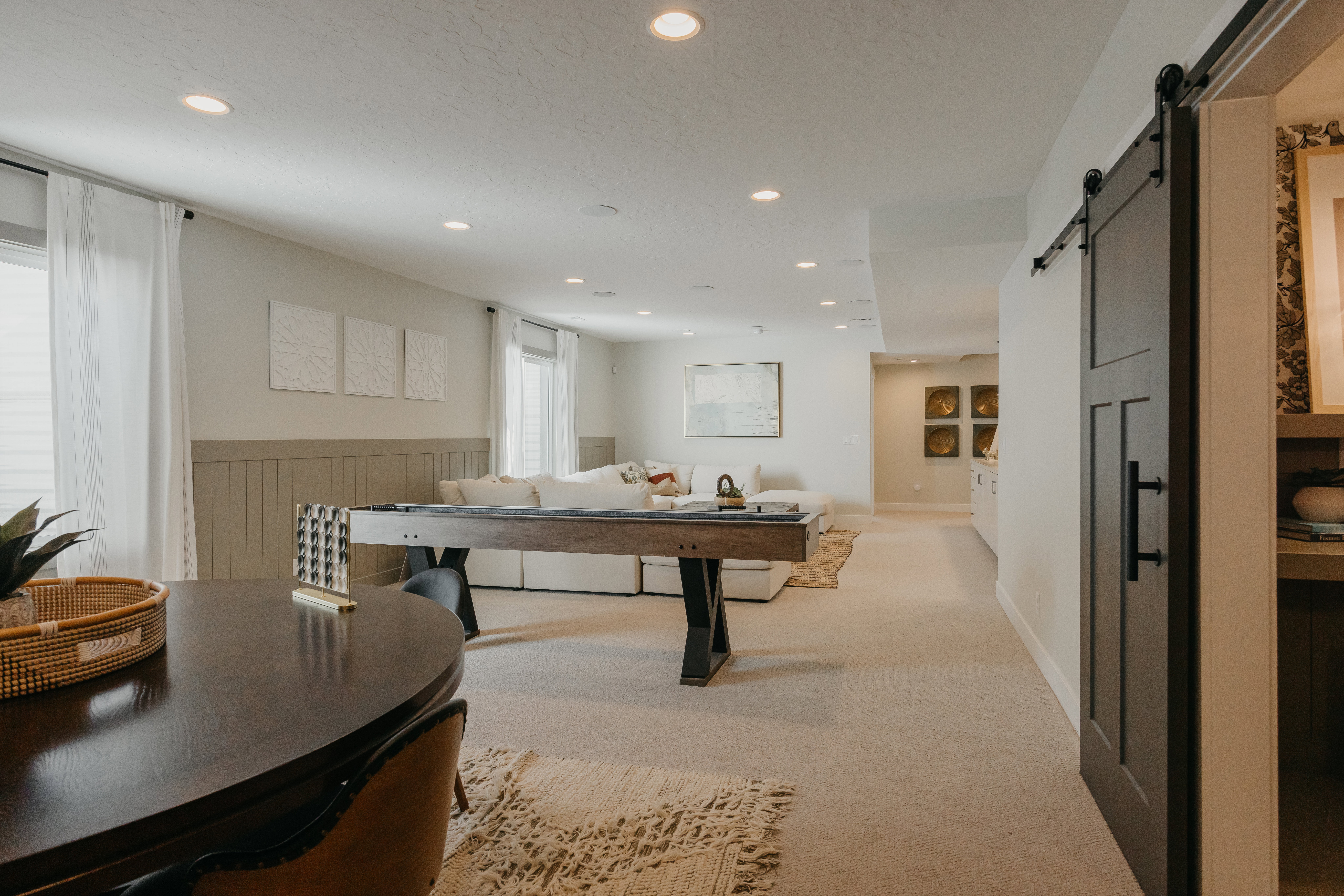 Spacious recreational room featuring recessed lighting, light-toned carpeting, and a dark wood-finish barn door