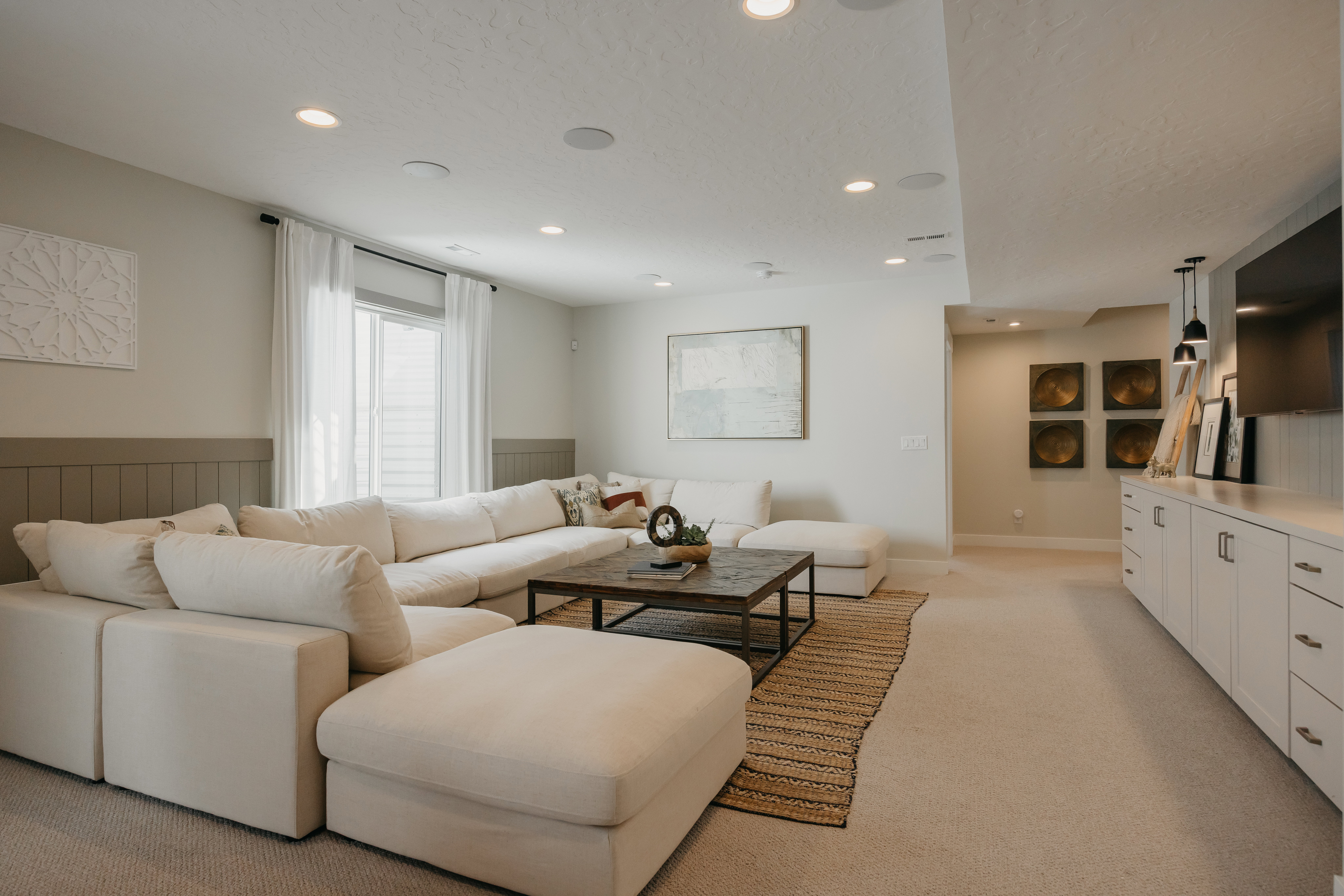 Spacious living area featuring recessed lighting, a window with natural light, a wood-paneled accent wall, and built-in cabinetry with a countertop