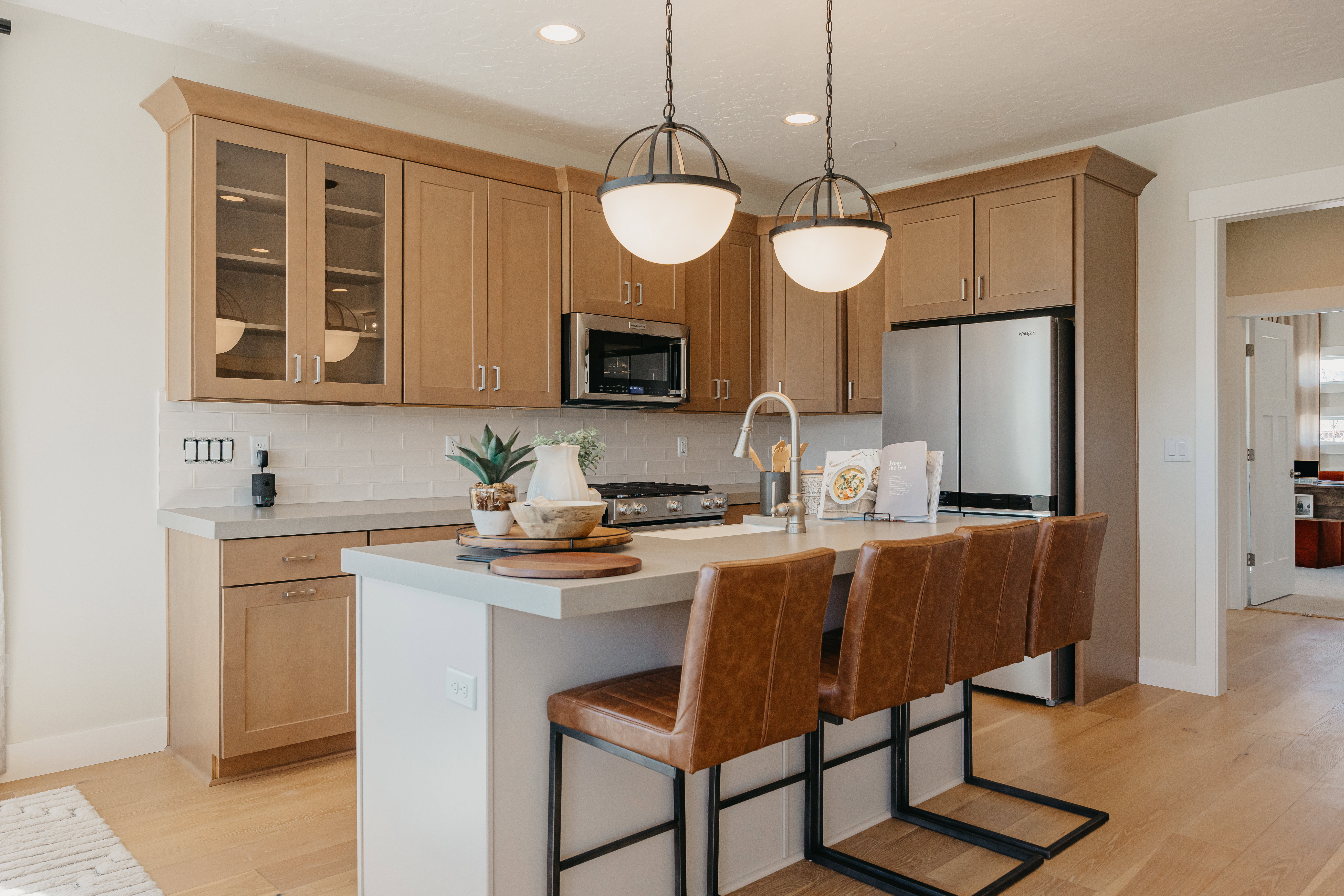 Kitchen featuring a central island with counter seating, stainless steel appliances, light wood-finish cabinetry, and a white subway tile backsplash